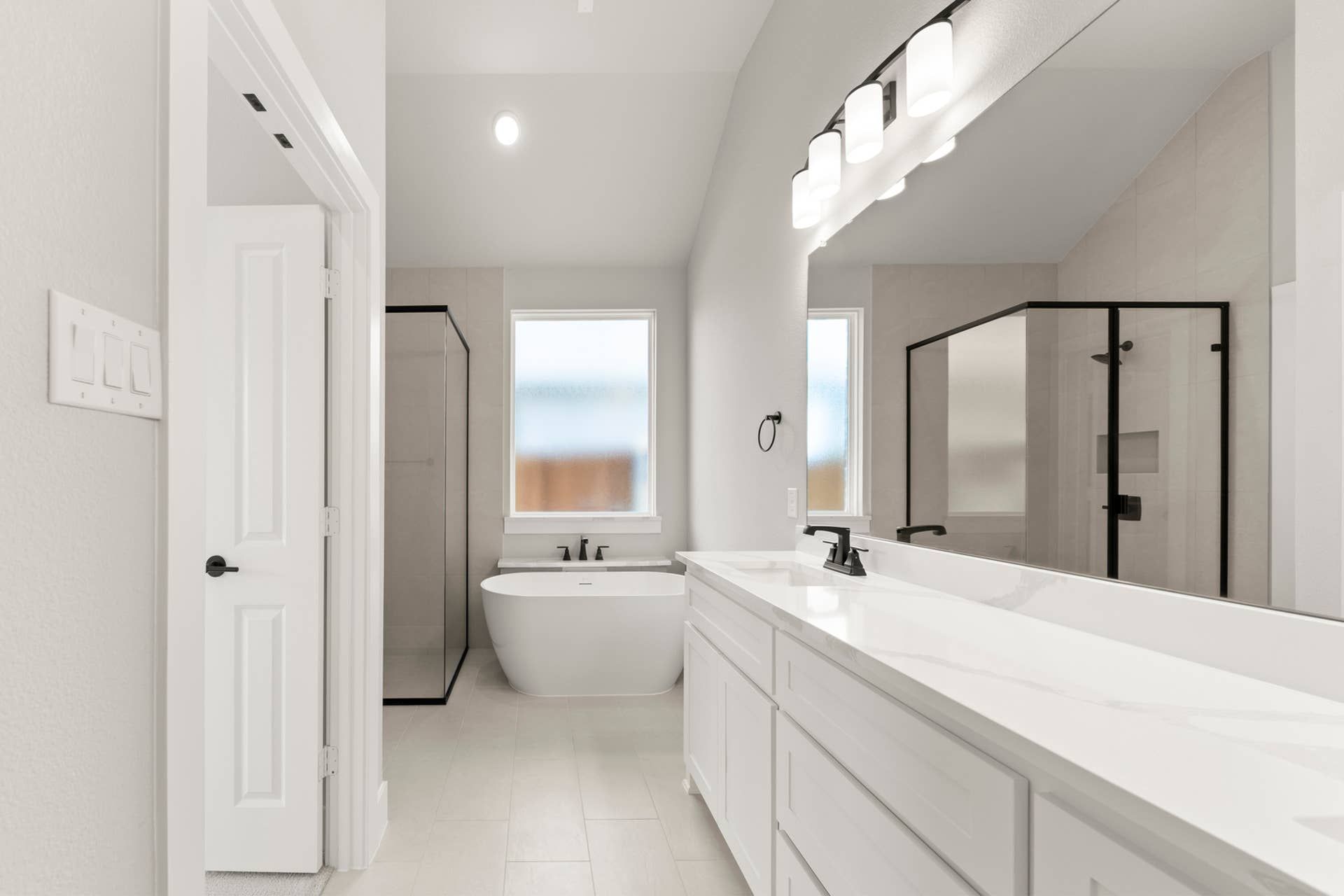 Modern bathroom with freestanding tub, glass shower, and double vanity.