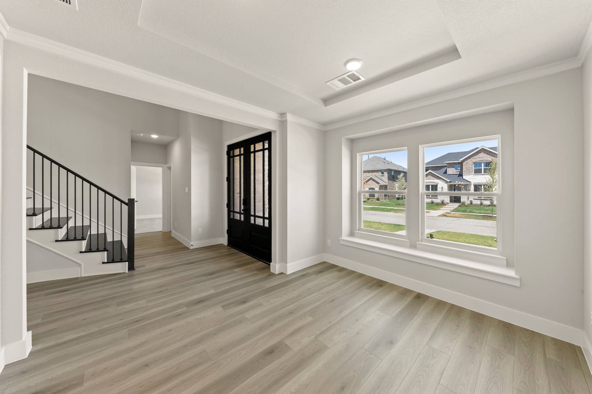 Elegant dining room with hardwood floors and large front-facing windows.