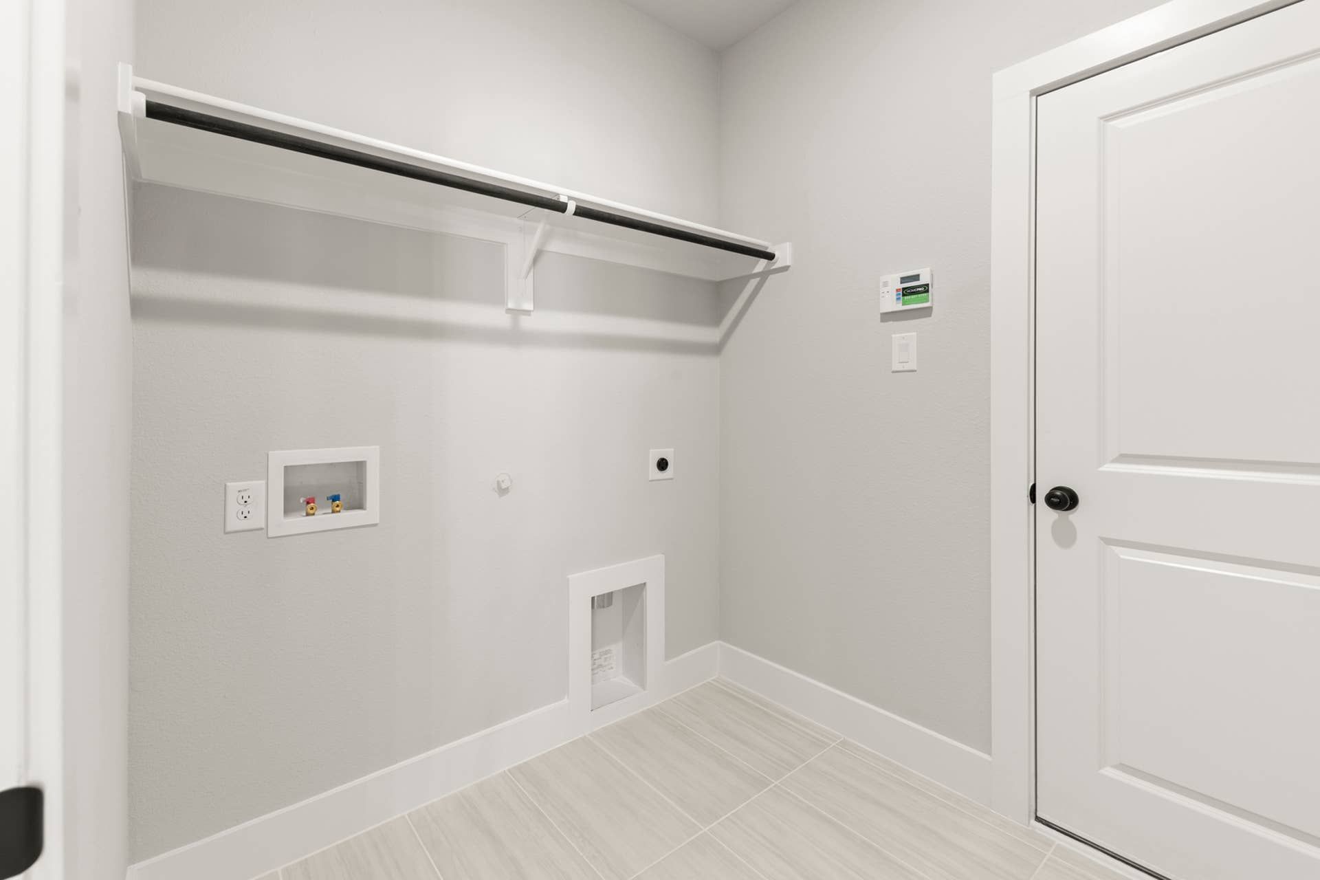 Spacious utility room with storage shelf and washing machine hookups.