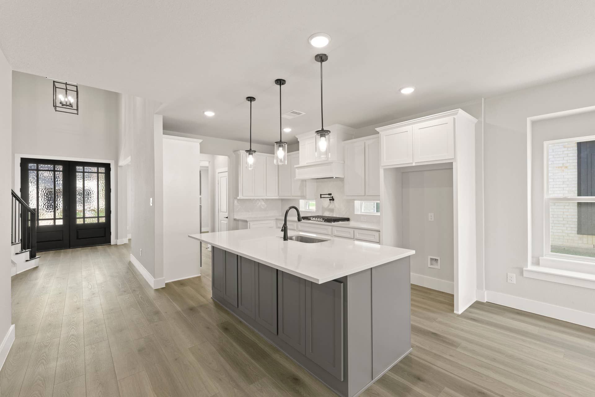 Modern kitchen with white cabinets, large island, and pendant lighting.