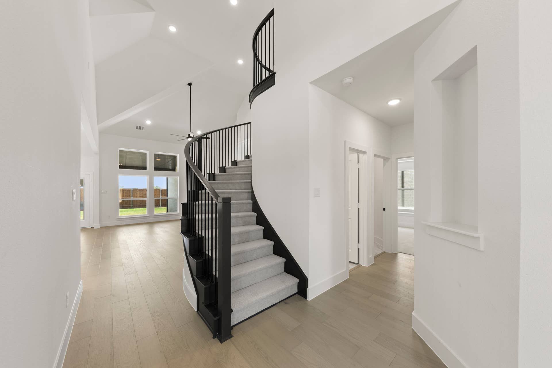 Spacious entryway with elegant curved staircase and high ceilings.