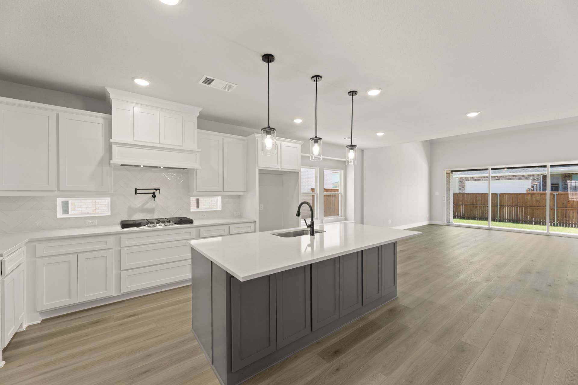Modern kitchen with island, pendant lighting, and large sliding glass doors.