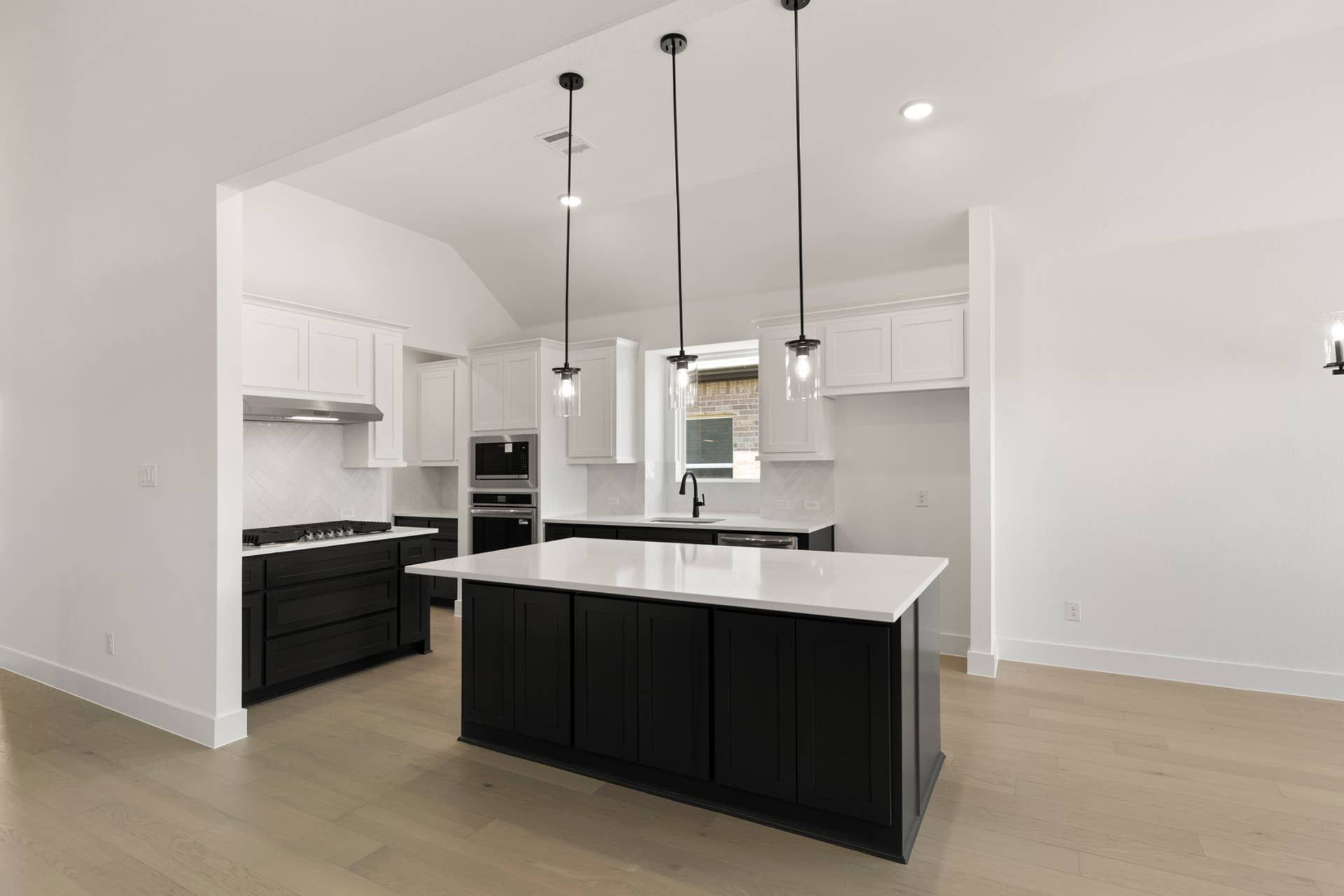 Modern kitchen with black and white cabinetry, island, and pendant lighting.