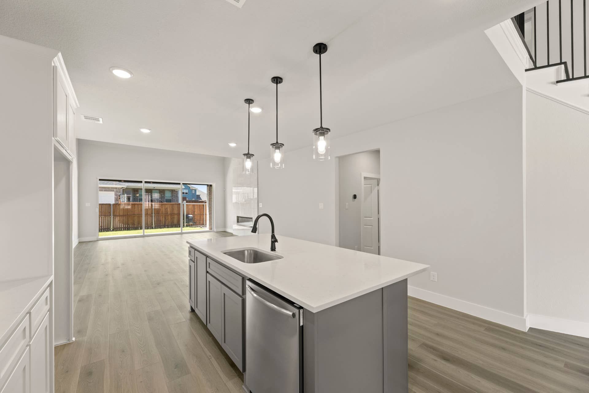 Modern kitchen with island, pendant lighting, and sliding glass doors.