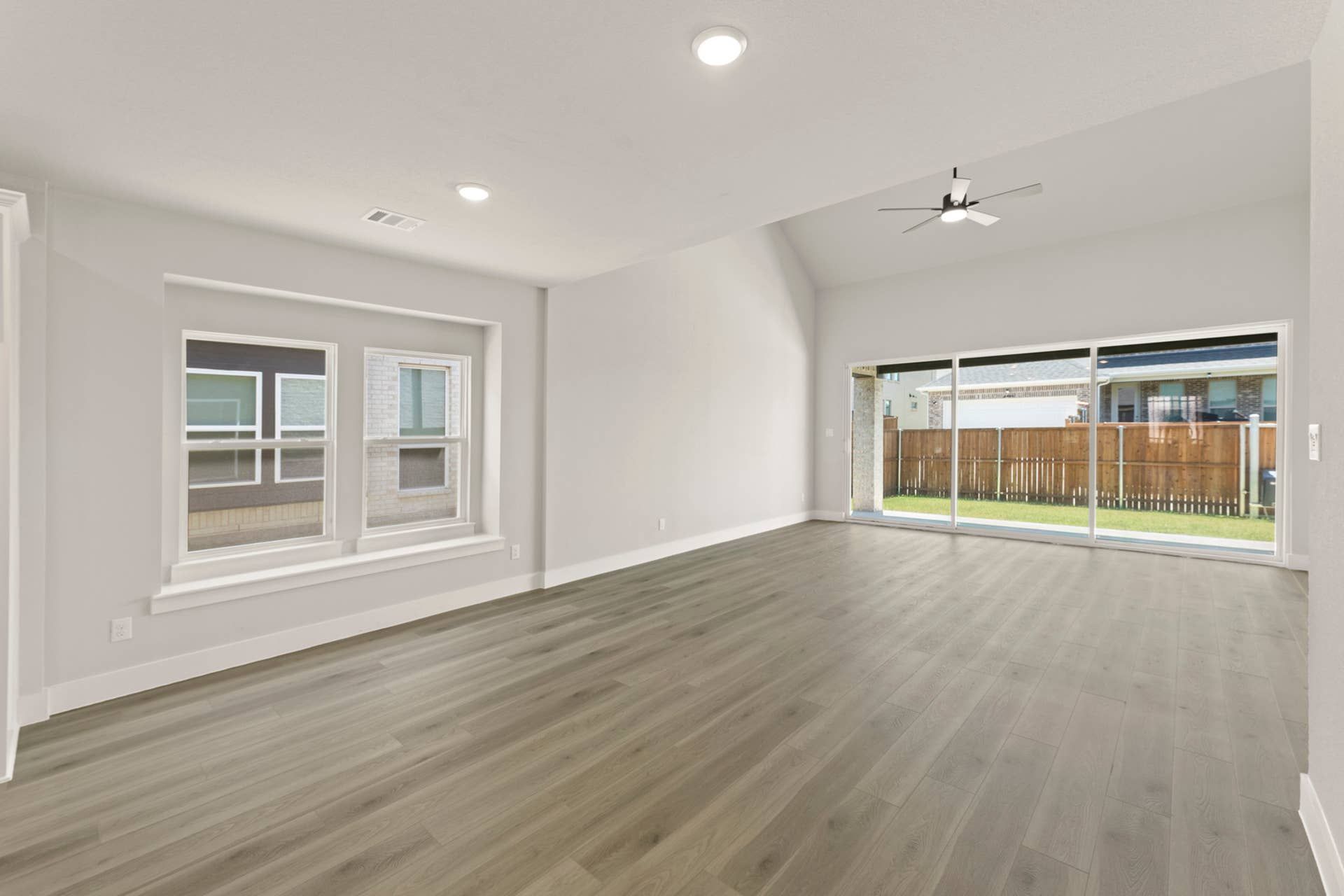 Spacious living area with large windows and wood flooring.