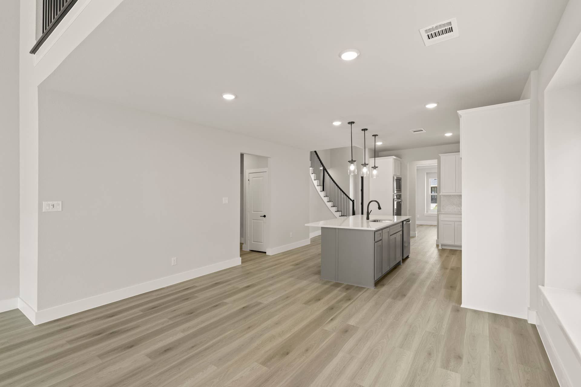 Modern kitchen interior with island, pendant lights, and light wood flooring.