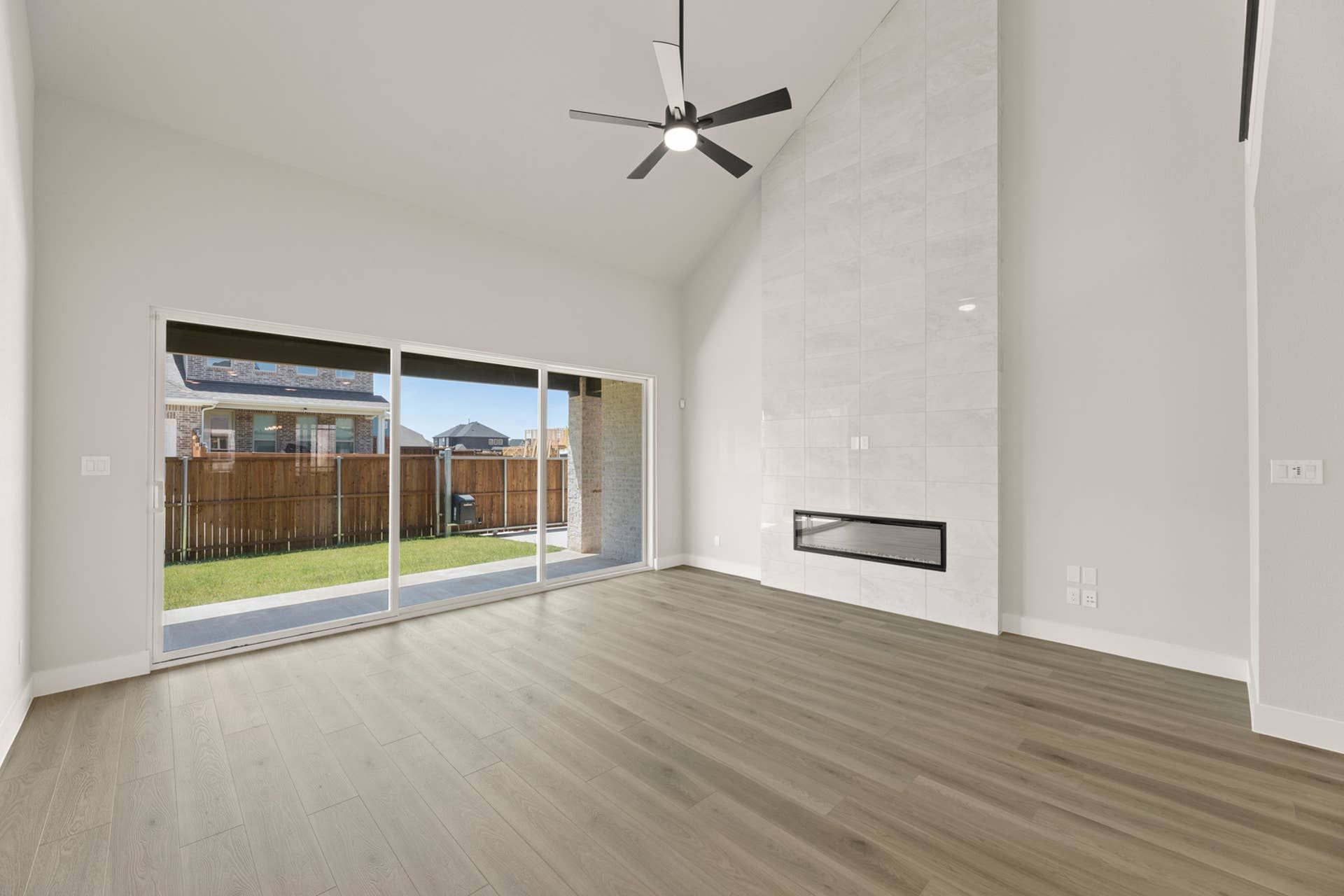 Spacious living room with large windows, modern fireplace, and ceiling fan.