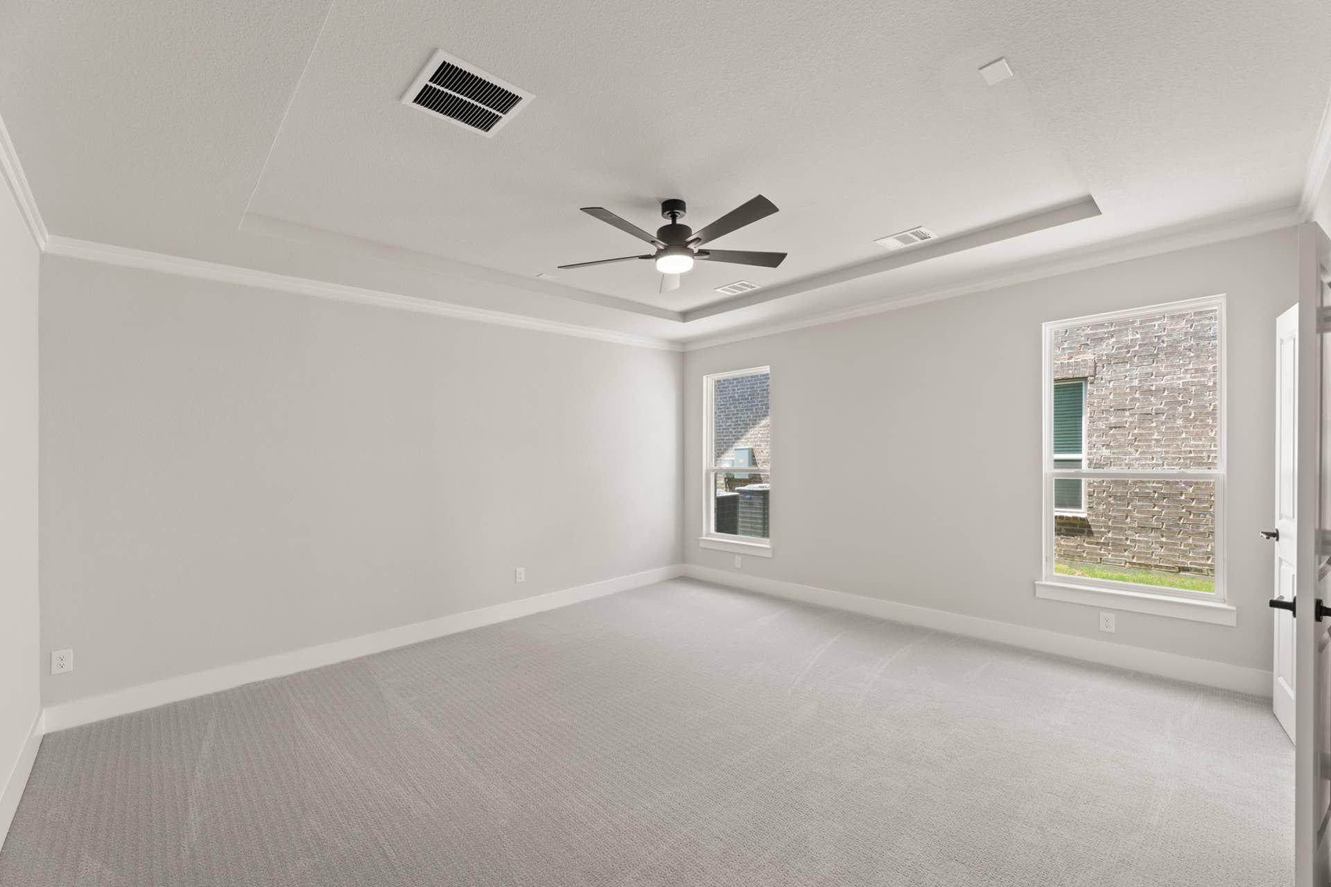 Spacious empty bedroom with ceiling fan and large windows.