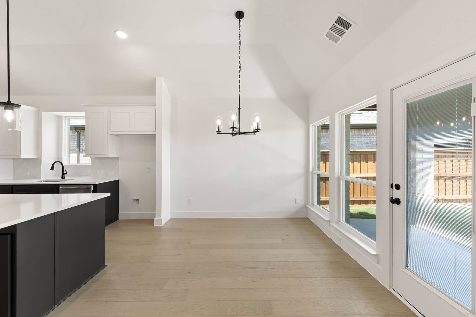 Modern kitchen and dining area with black cabinetry and large windows.