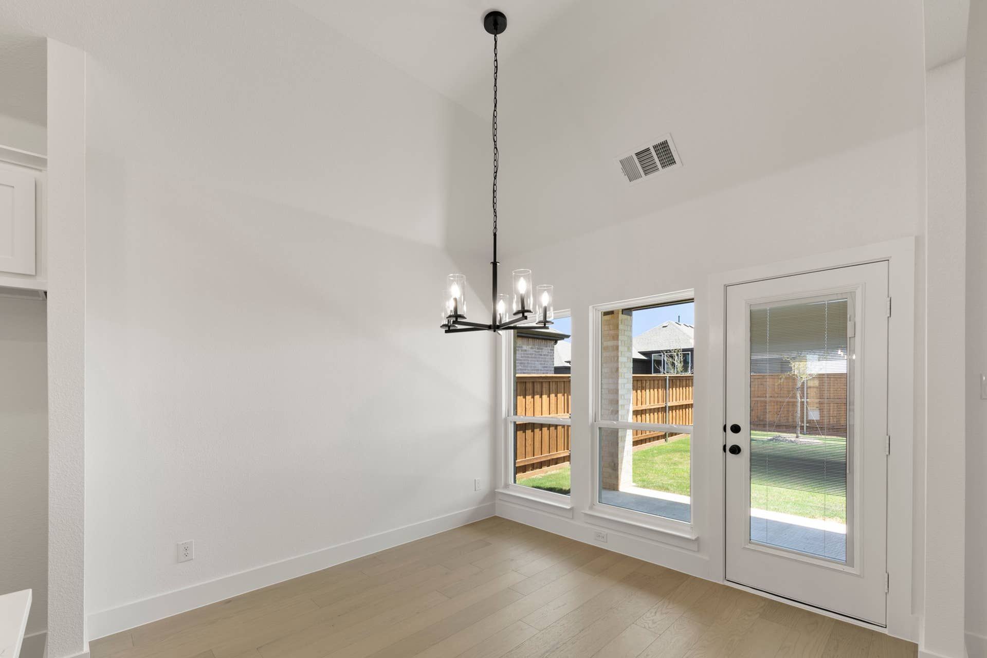 Bright dining area with modern chandelier and glass door to backyard.