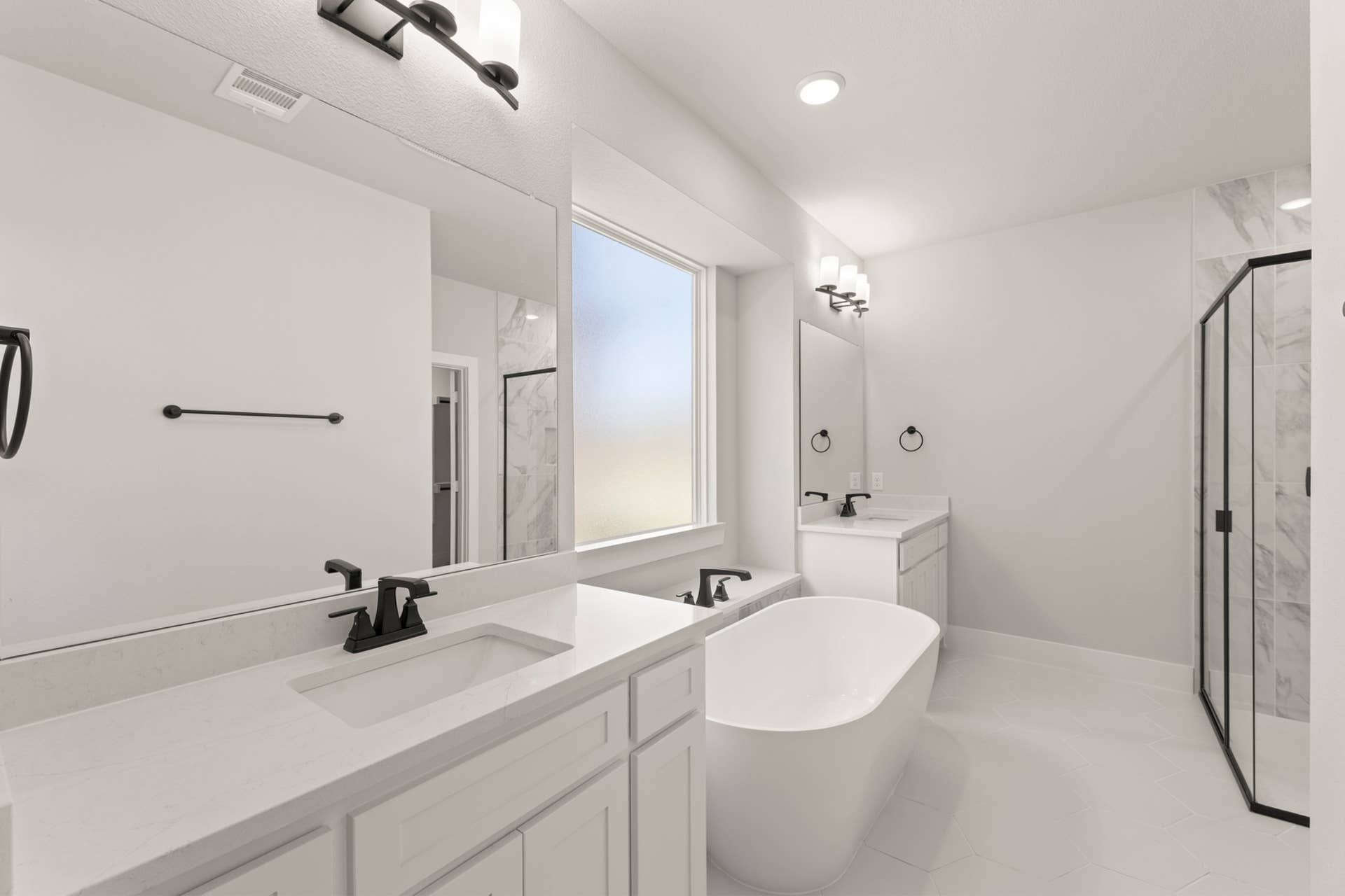 Modern bathroom with freestanding tub, double vanity, and glass-enclosed shower.