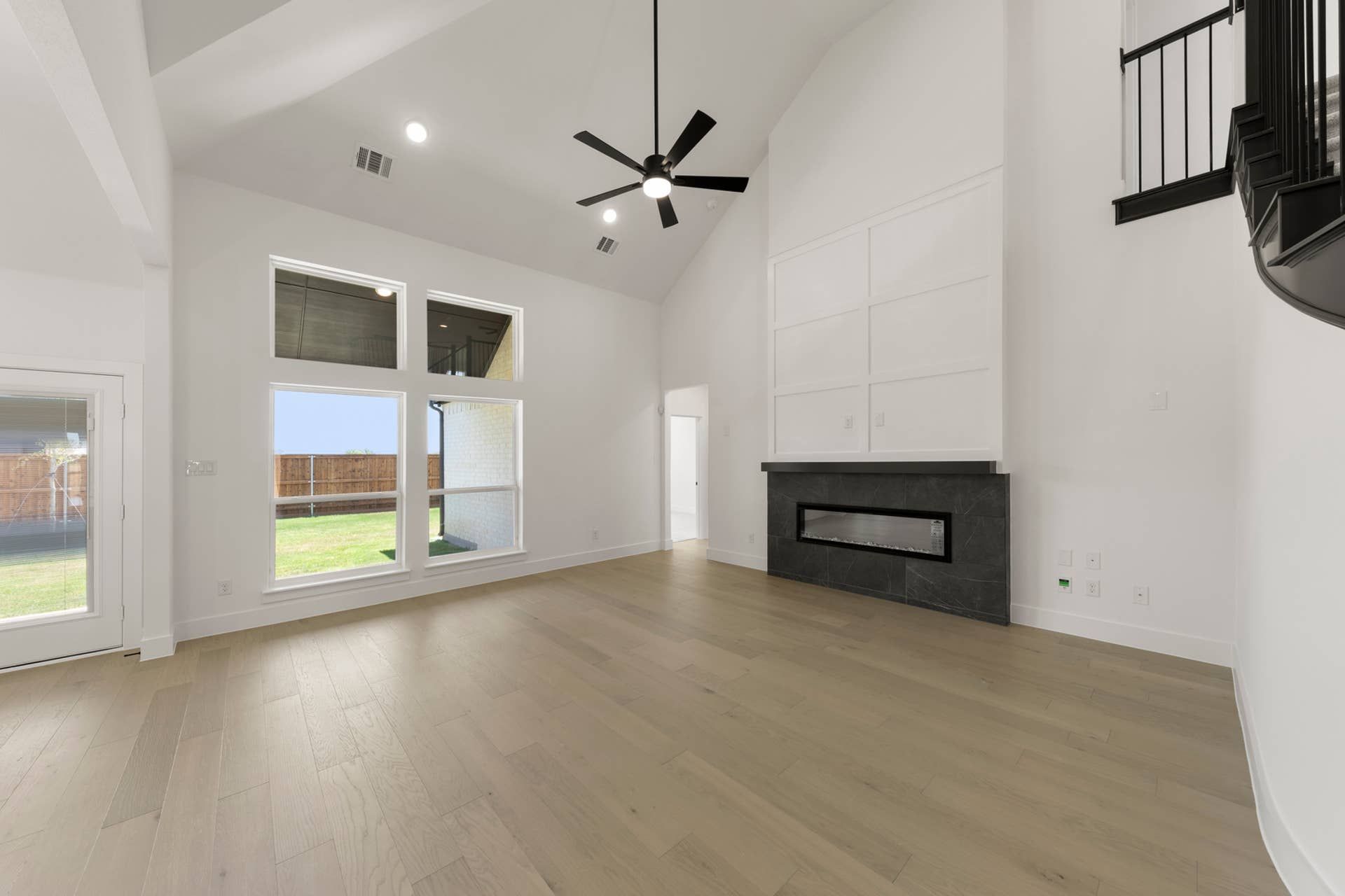 Spacious living room with high ceiling, modern fireplace, and large windows.