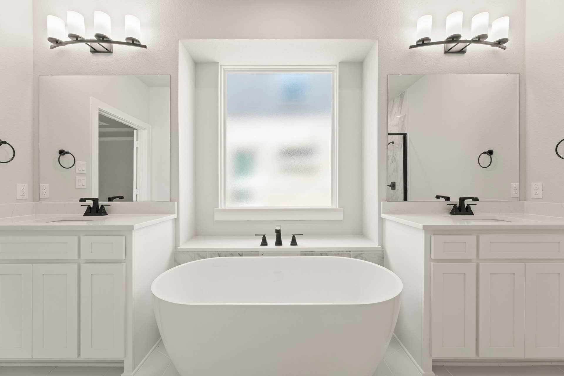 Modern bathroom with freestanding tub, dual sinks, and large mirrors.