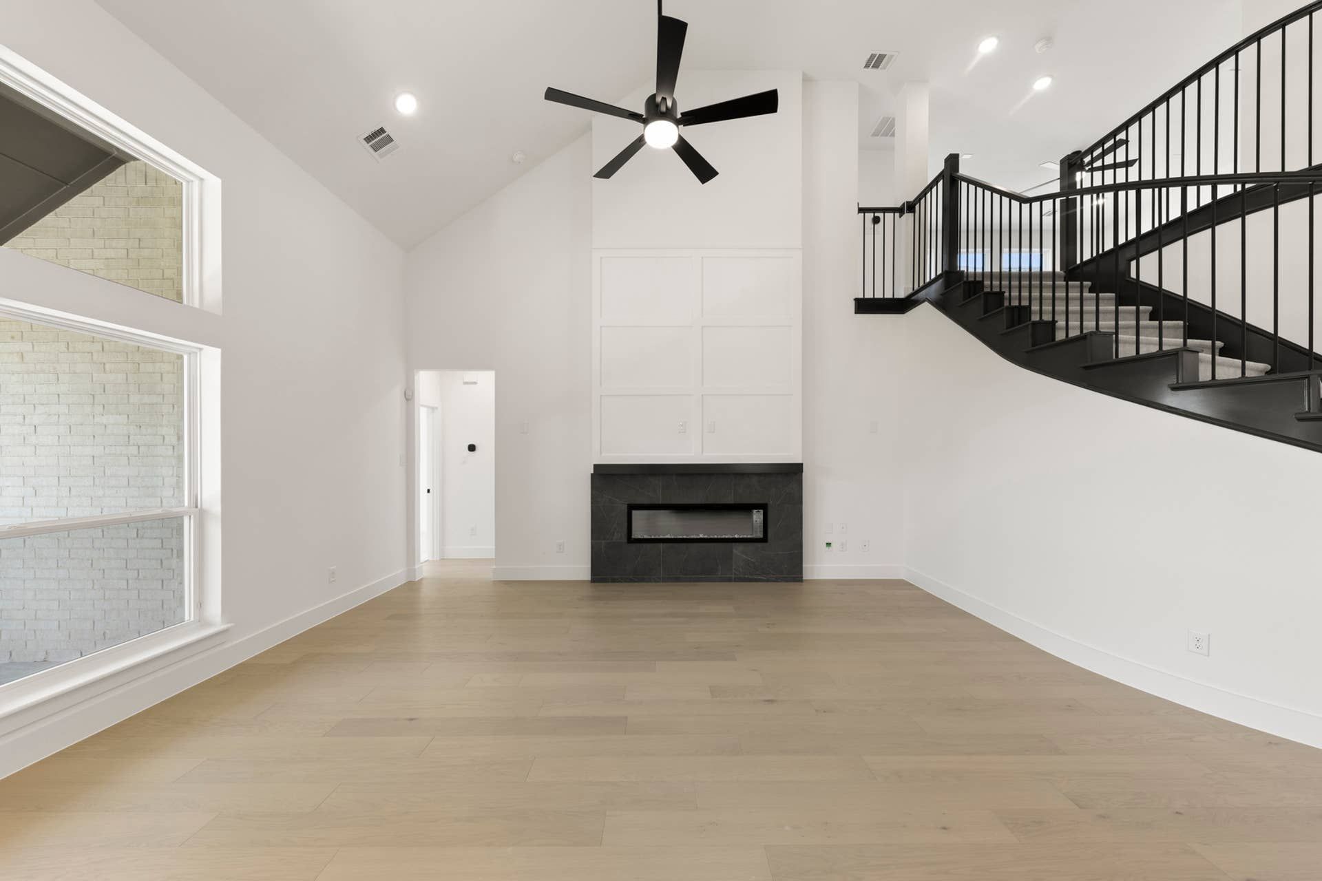 Spacious modern living room with sleek staircase and contemporary fireplace.