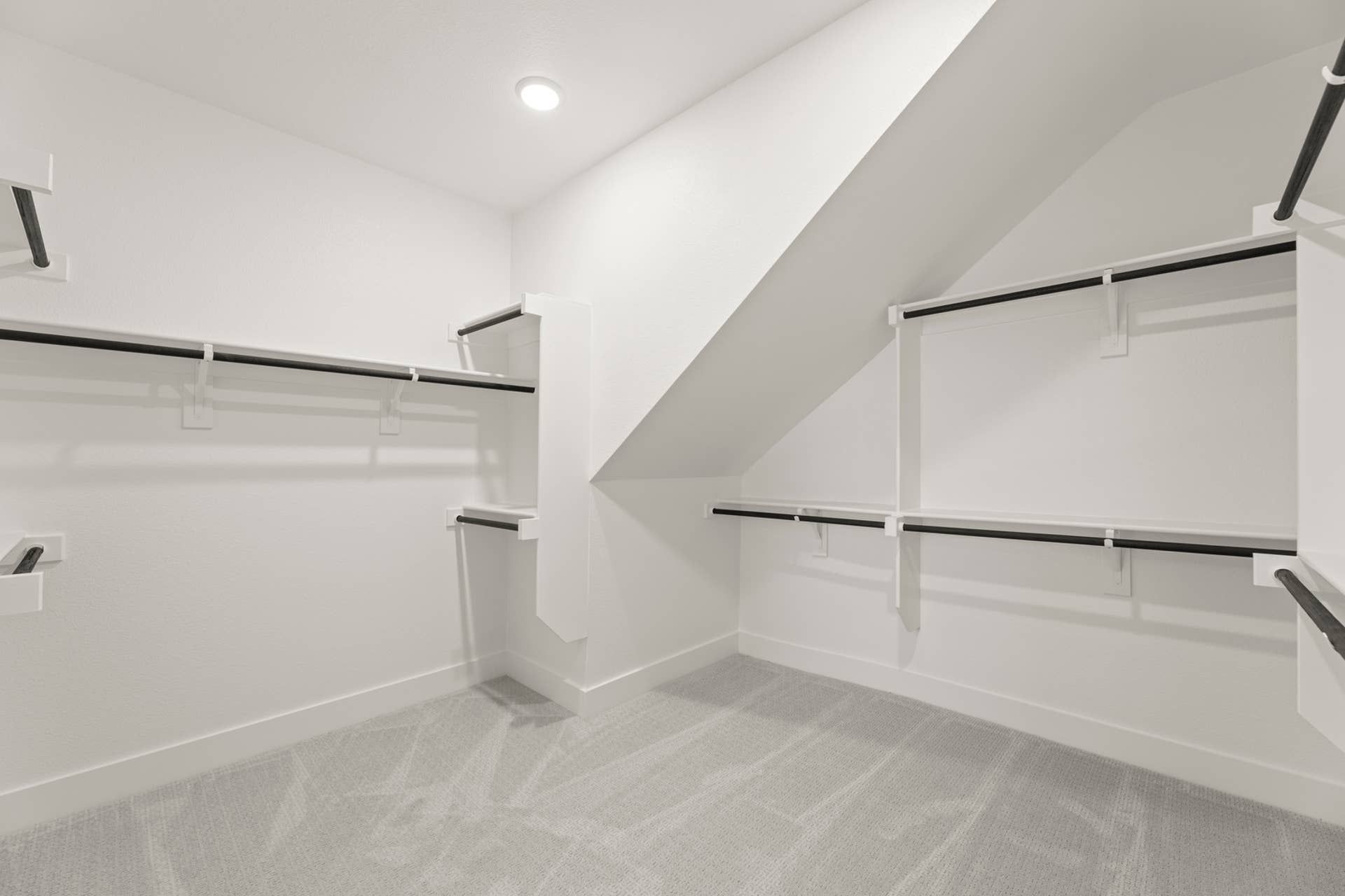 Spacious walk-in closet with angled ceiling and ample shelving.