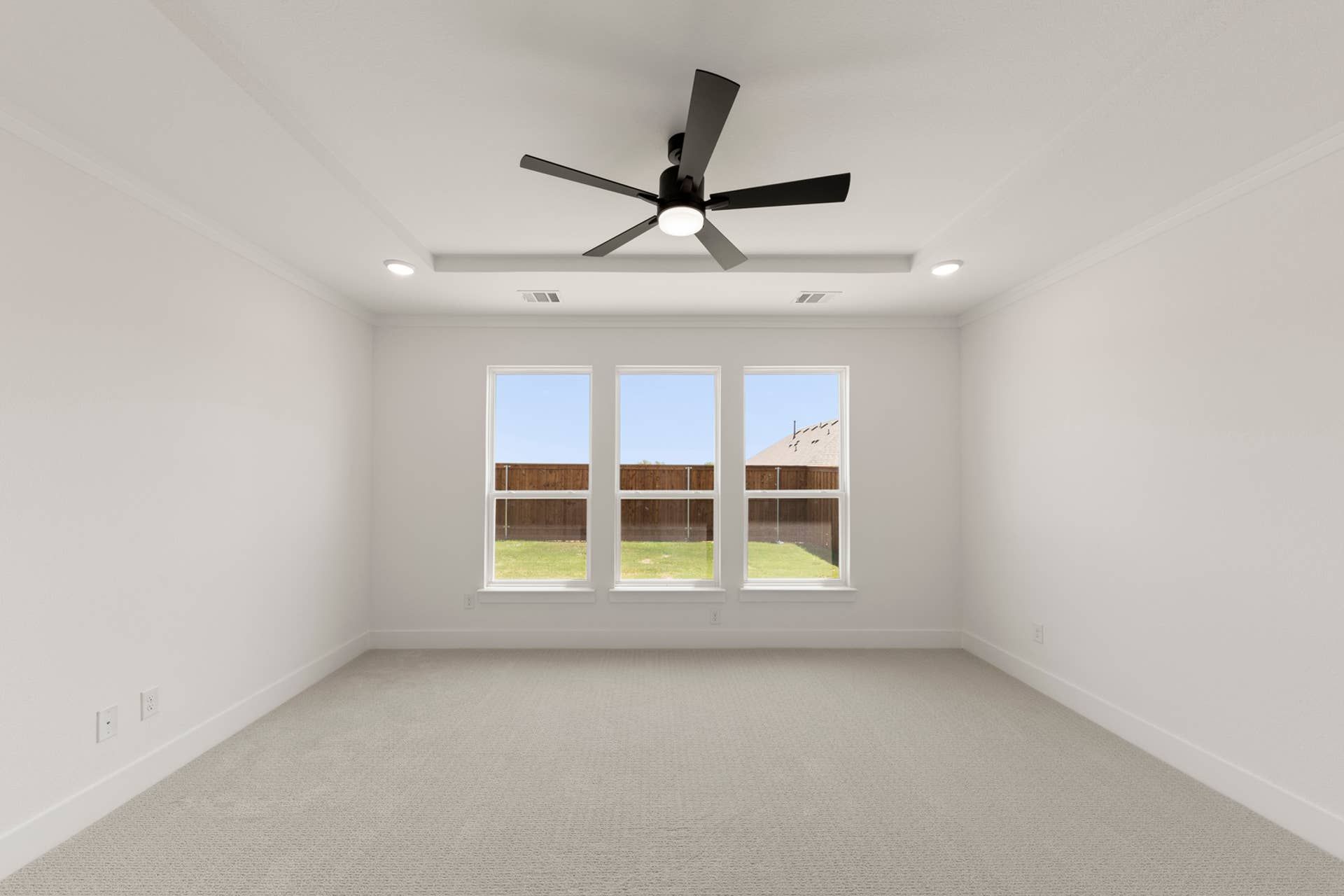Spacious bedroom with large windows and ceiling fan in modern home interior.