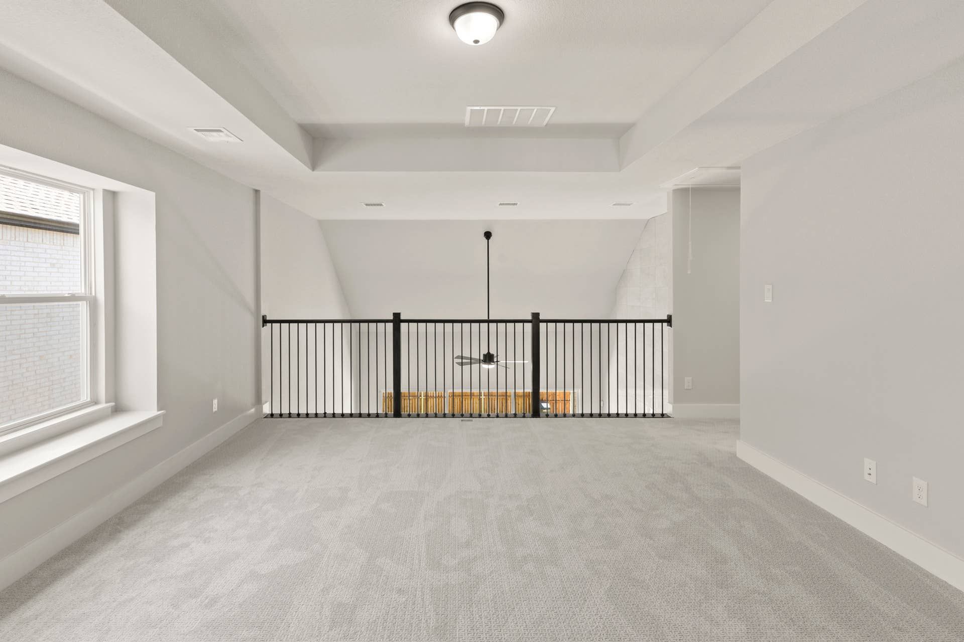 Spacious loft area with carpet flooring and black metal railing.