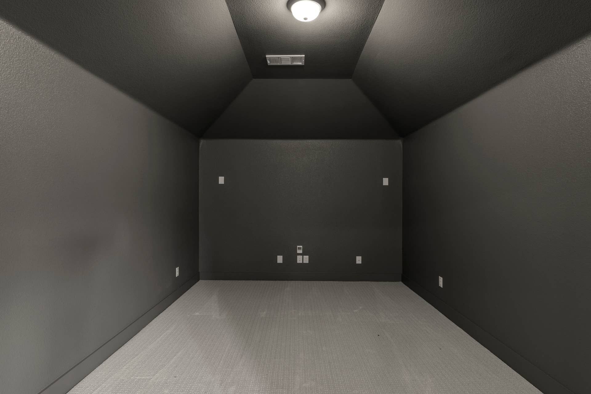 Representative photo of a dark, empty room with recessed lighting.