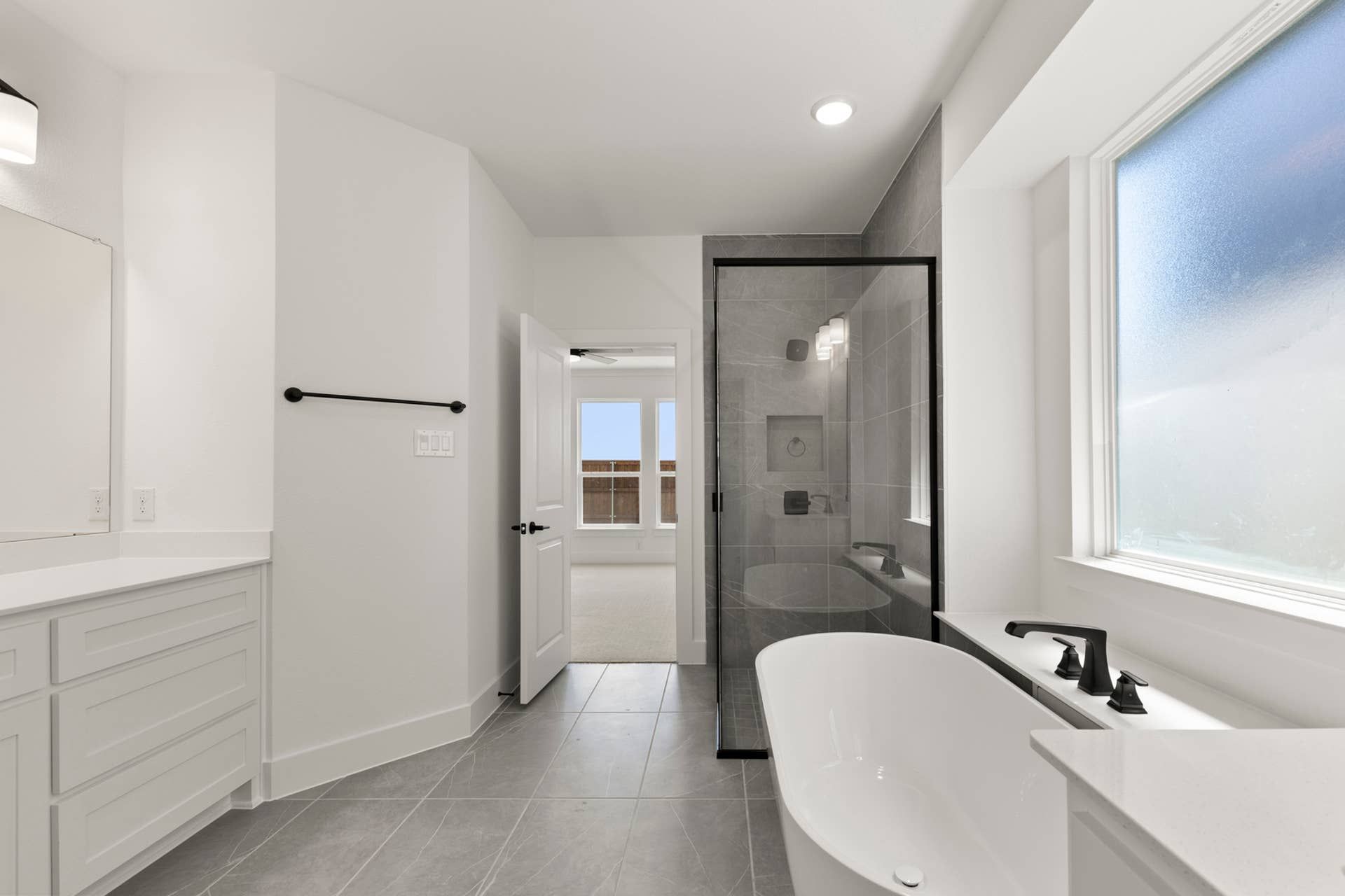 Modern bathroom with freestanding tub, glass shower, and large window.