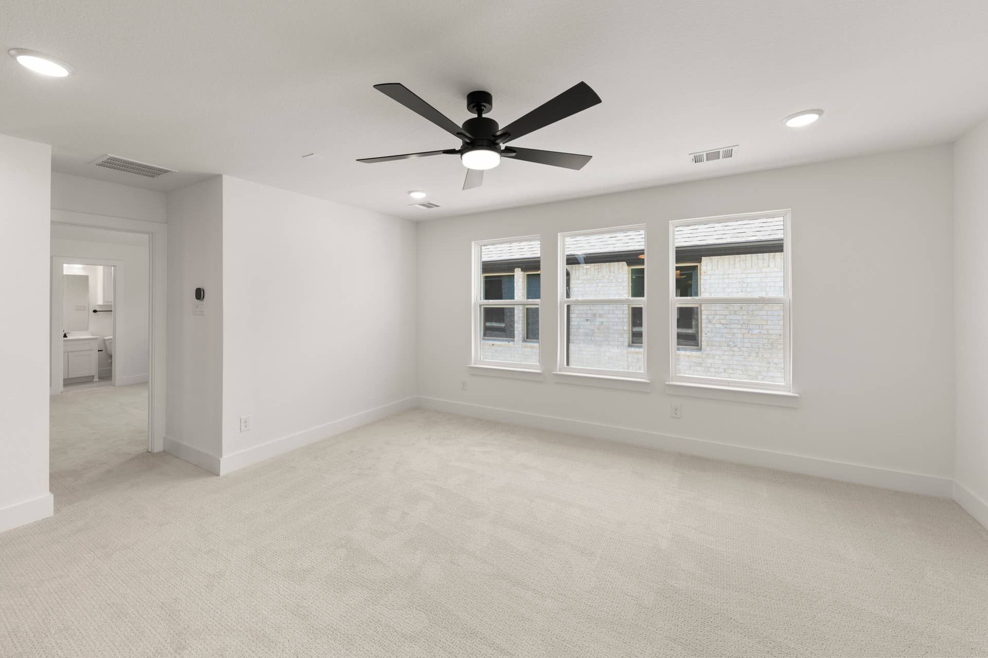 Spacious bedroom with ceiling fan and large windows for natural light.