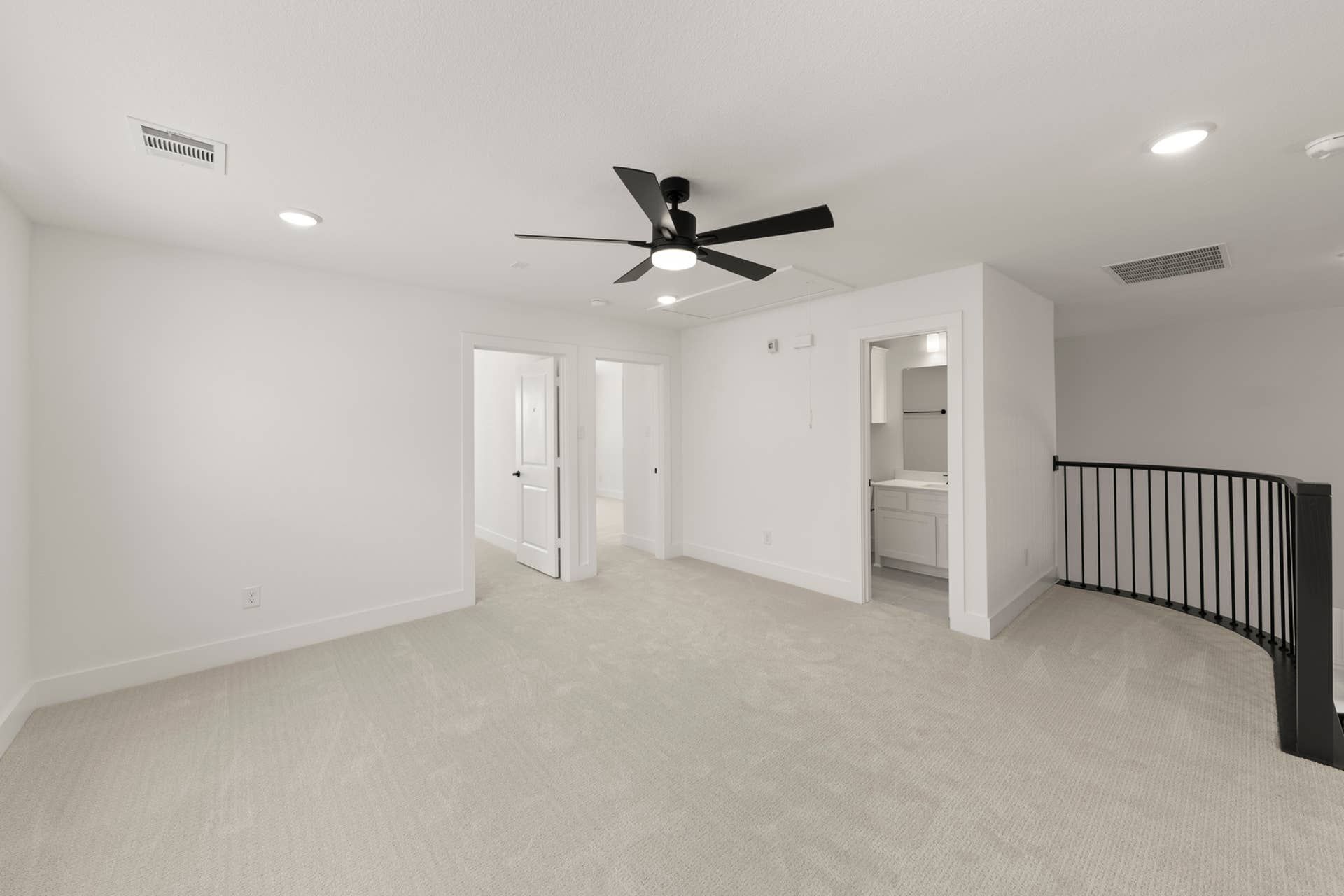Spacious interior with carpet flooring, ceiling fan, and adjacent bathroom.