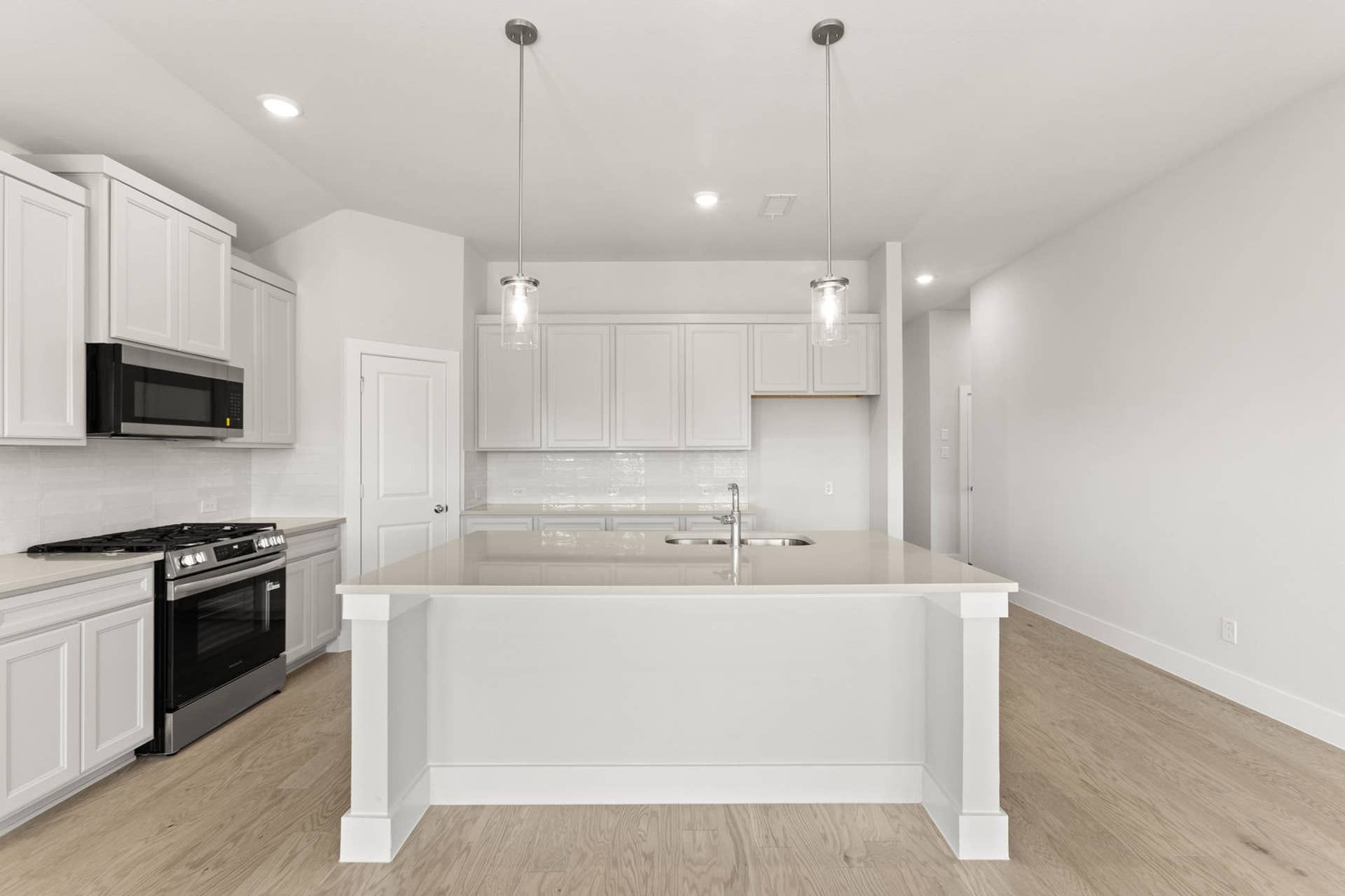 Modern kitchen with white cabinetry, island, and pendant lighting.