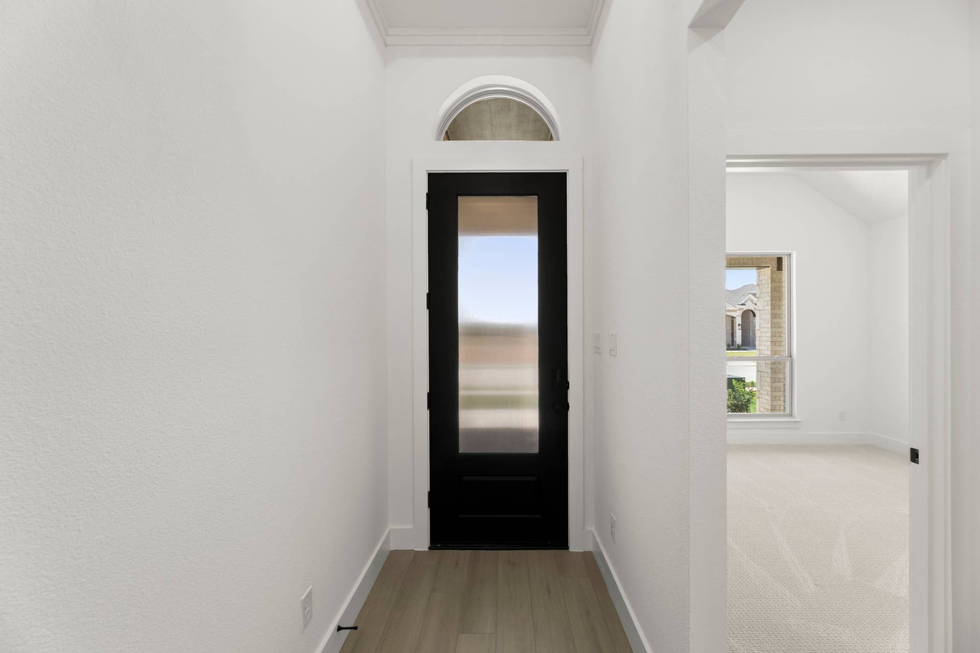 Interior entryway with black door and arched transom window.