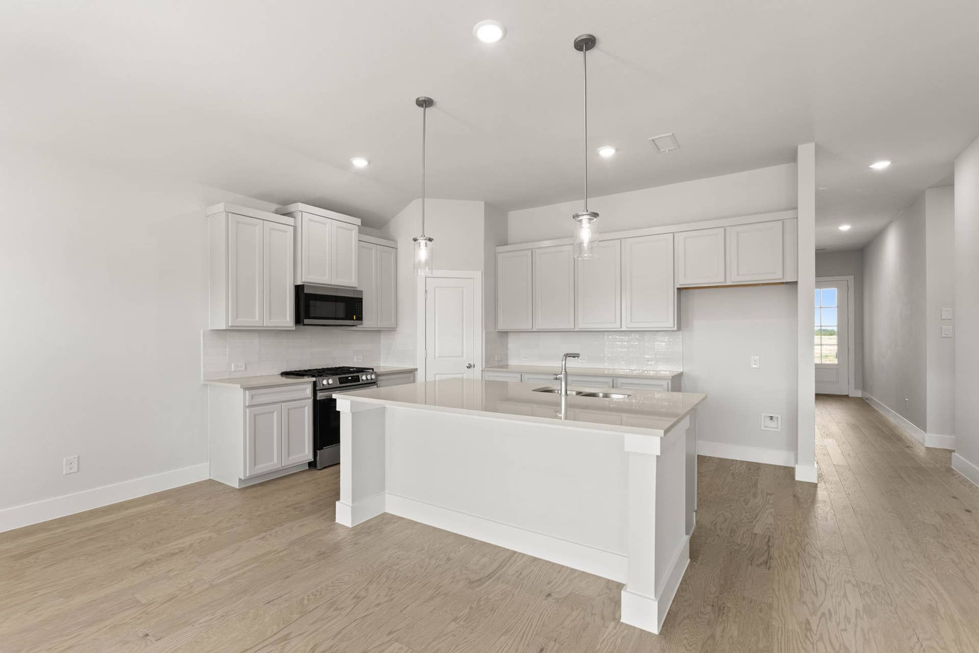 Modern kitchen with white cabinets, island, and pendant lighting.
