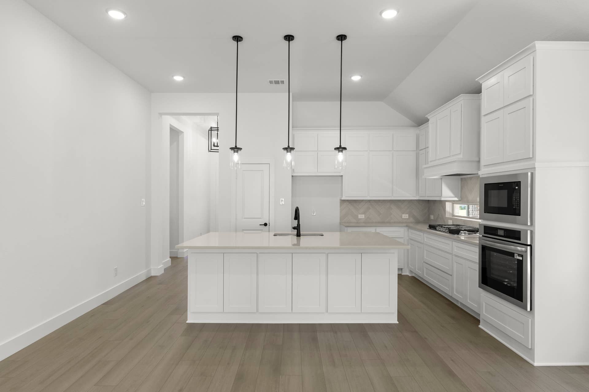 Modern kitchen with white cabinetry, island, and pendant lighting.