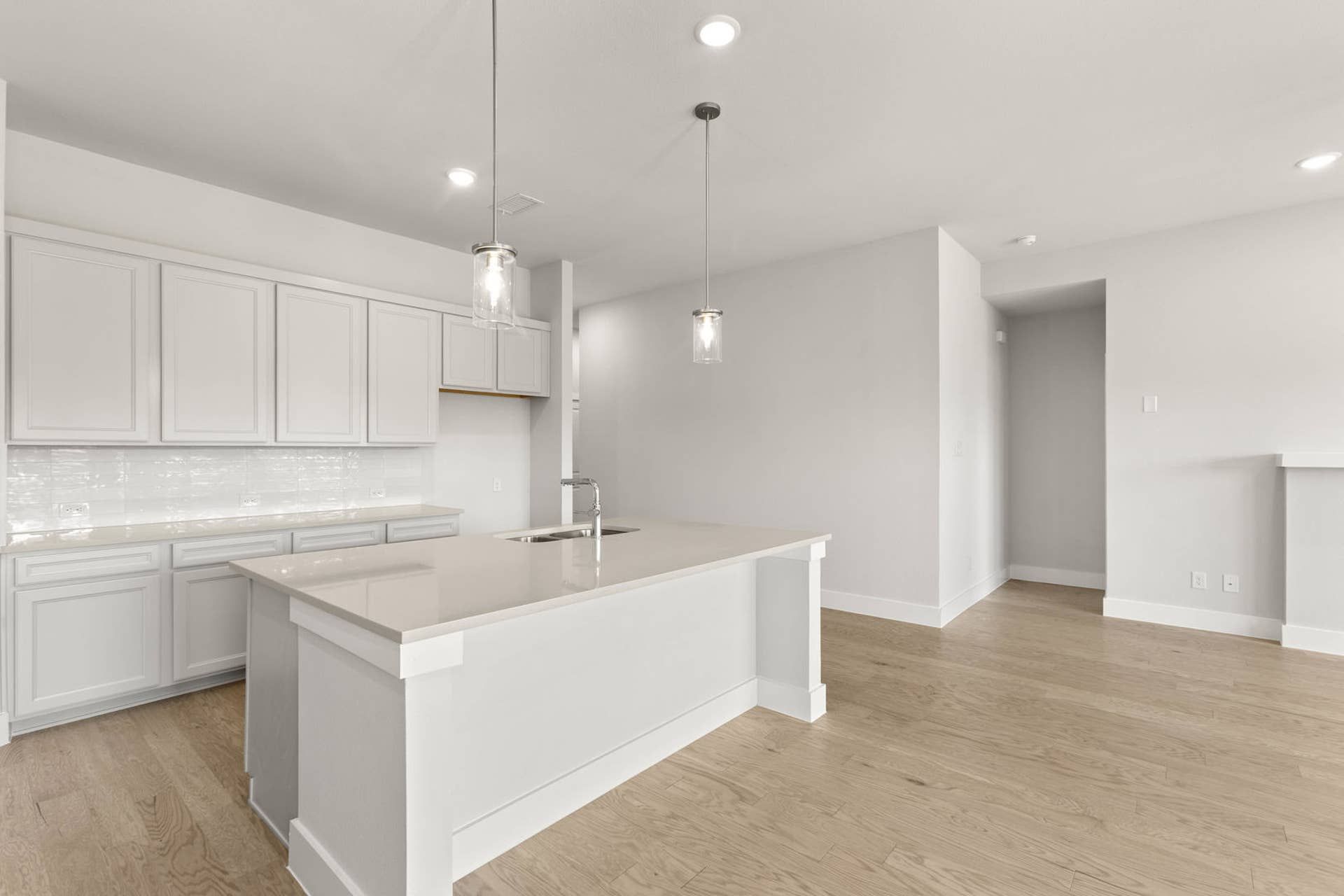 Modern kitchen with white cabinetry, island, and sleek pendant lighting.