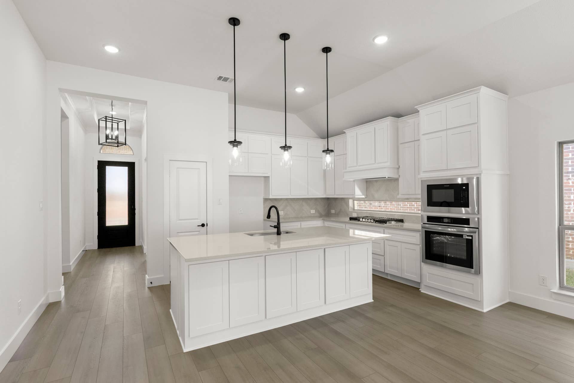 Modern kitchen with white cabinetry, island, and pendant lighting.