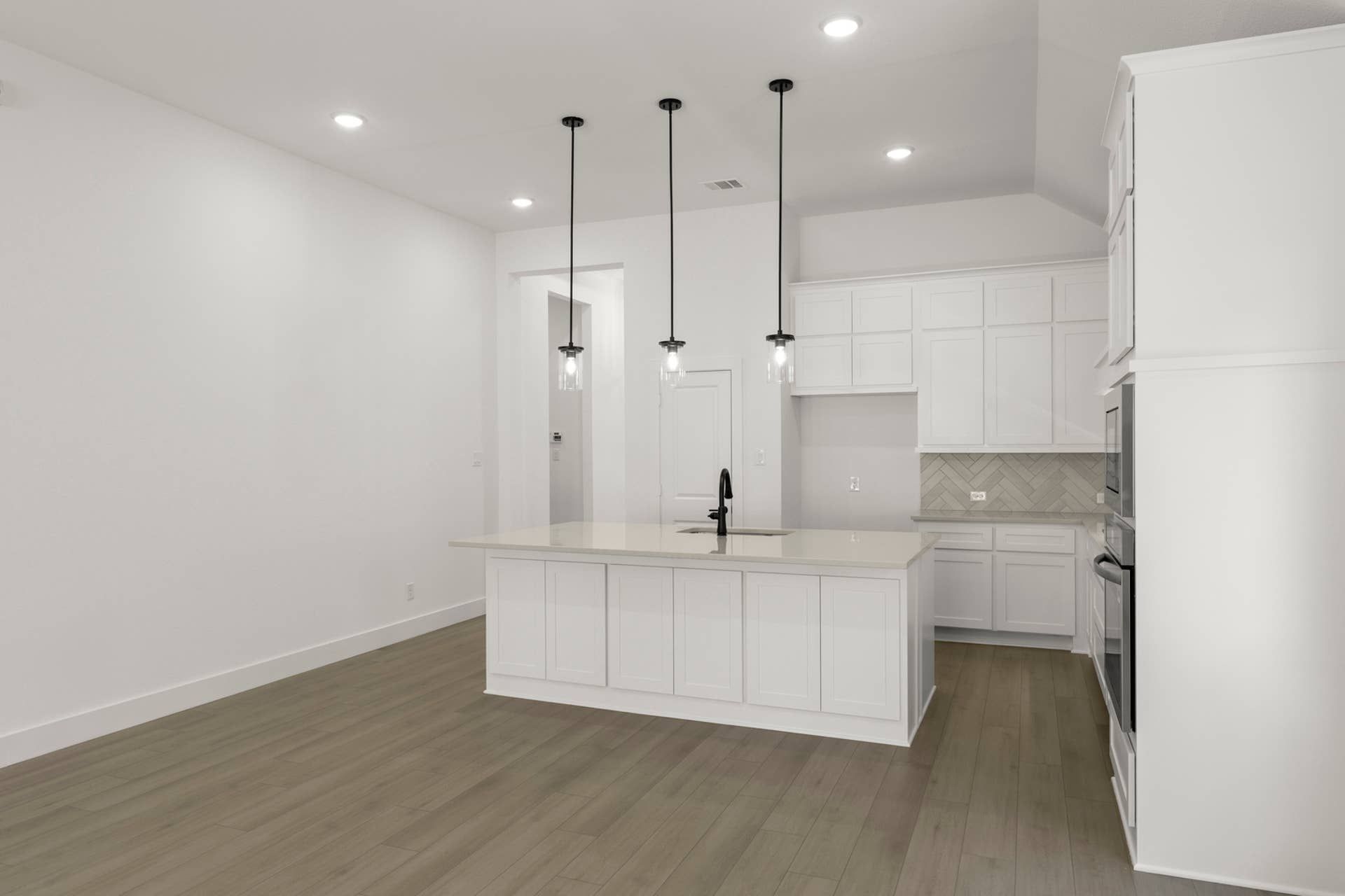 Modern kitchen with pendant lights and white cabinetry.