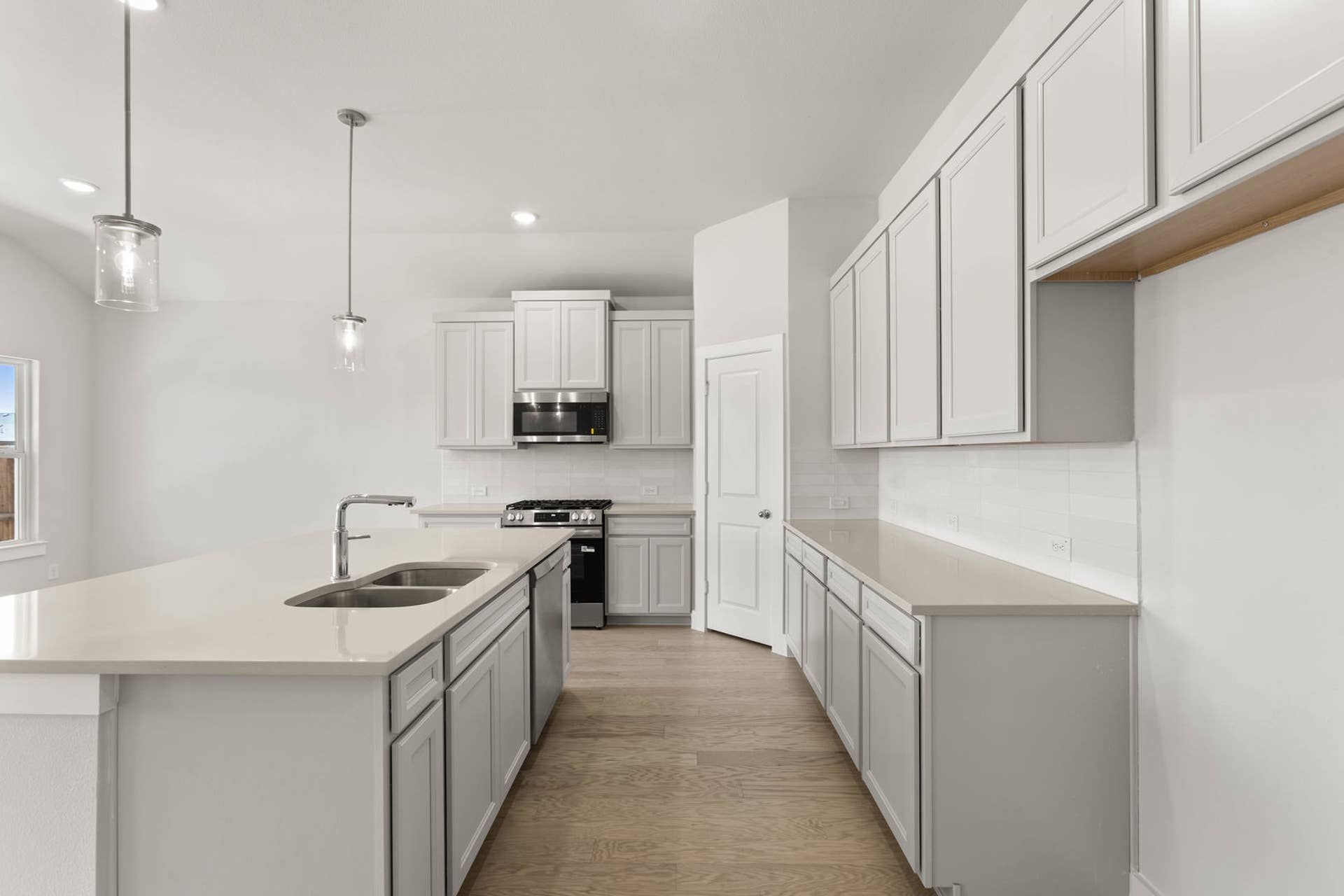 Modern kitchen with white cabinetry, island sink, and pendant lighting.