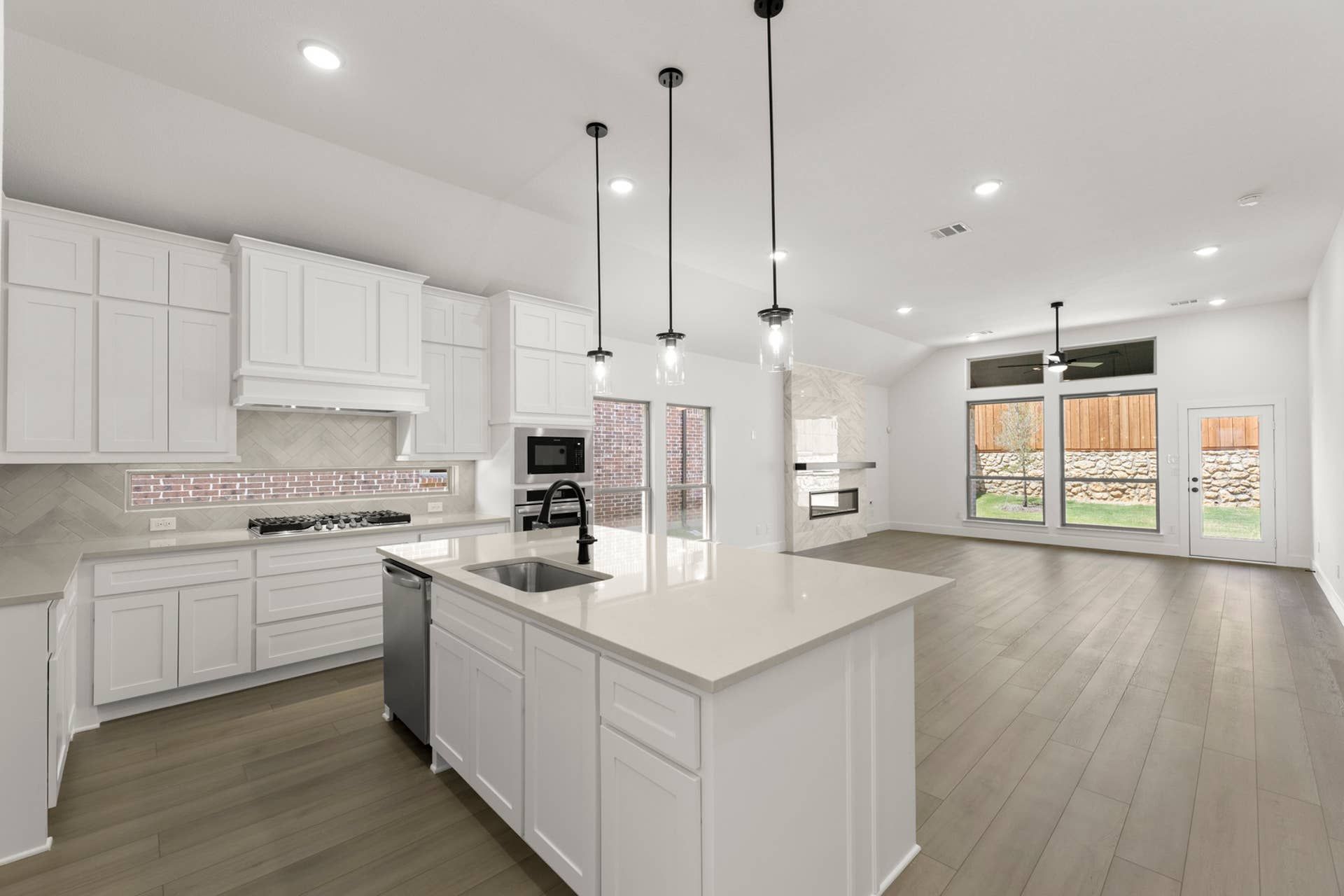 Modern kitchen with white cabinetry, island, and pendant lighting in open floor plan.