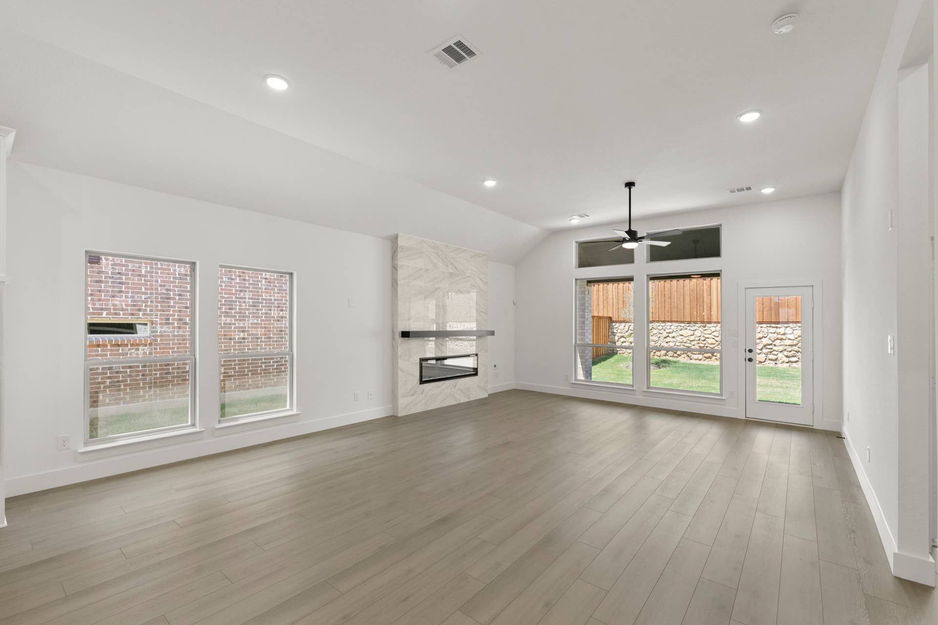 Spacious modern interior with large windows, hardwood floors, and a sleek fireplace.