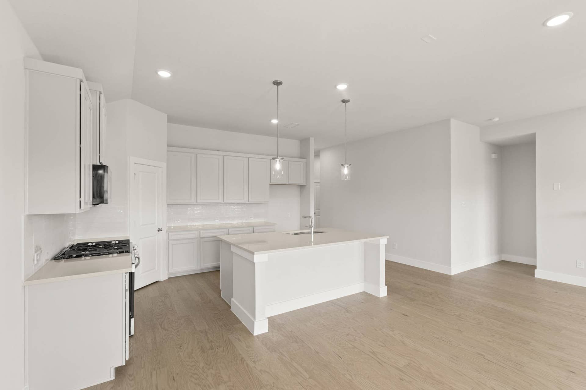 Modern kitchen with white cabinetry, island, and pendant lighting.