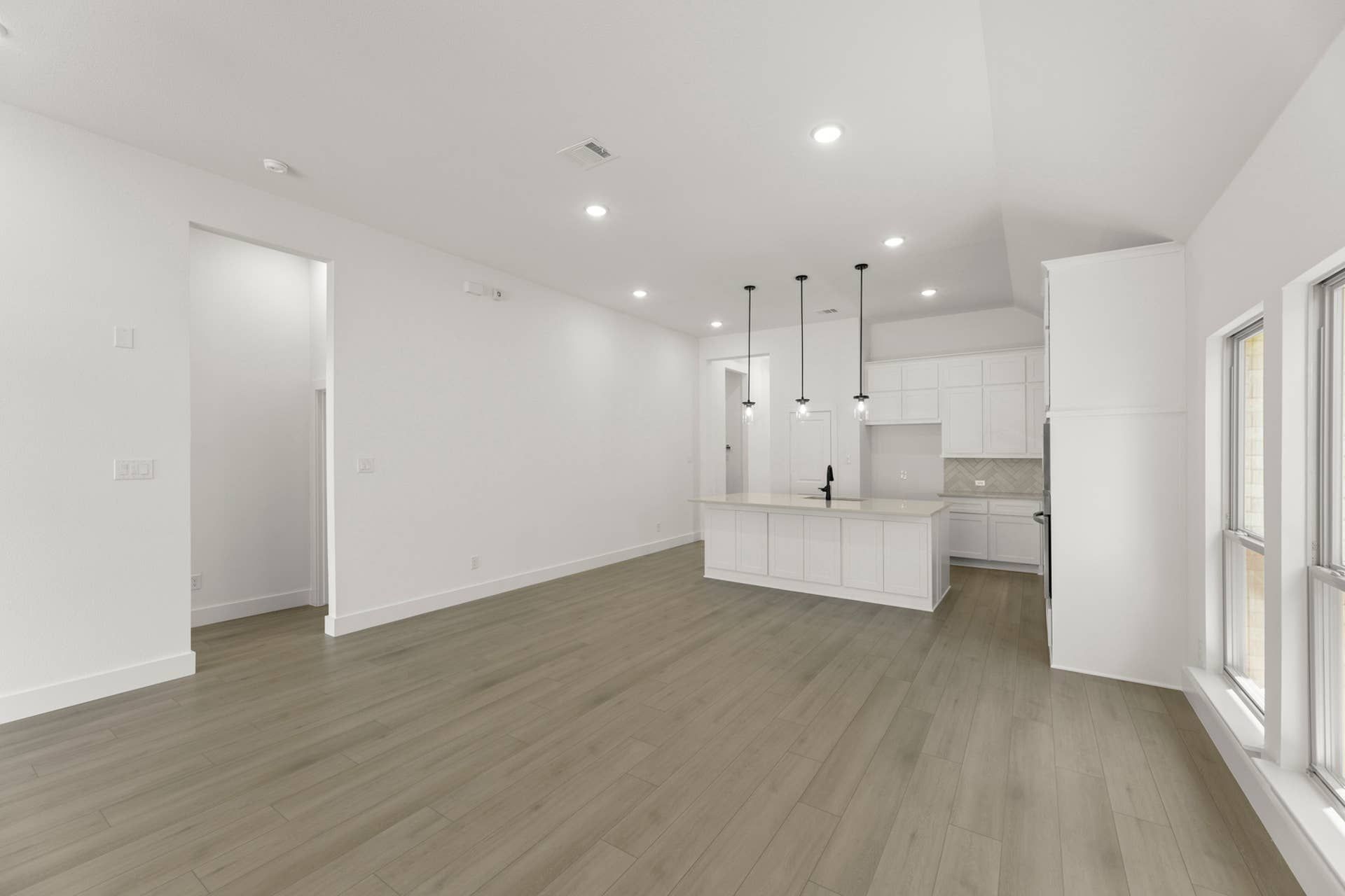Spacious open-concept interior with modern kitchen and pendant lighting.