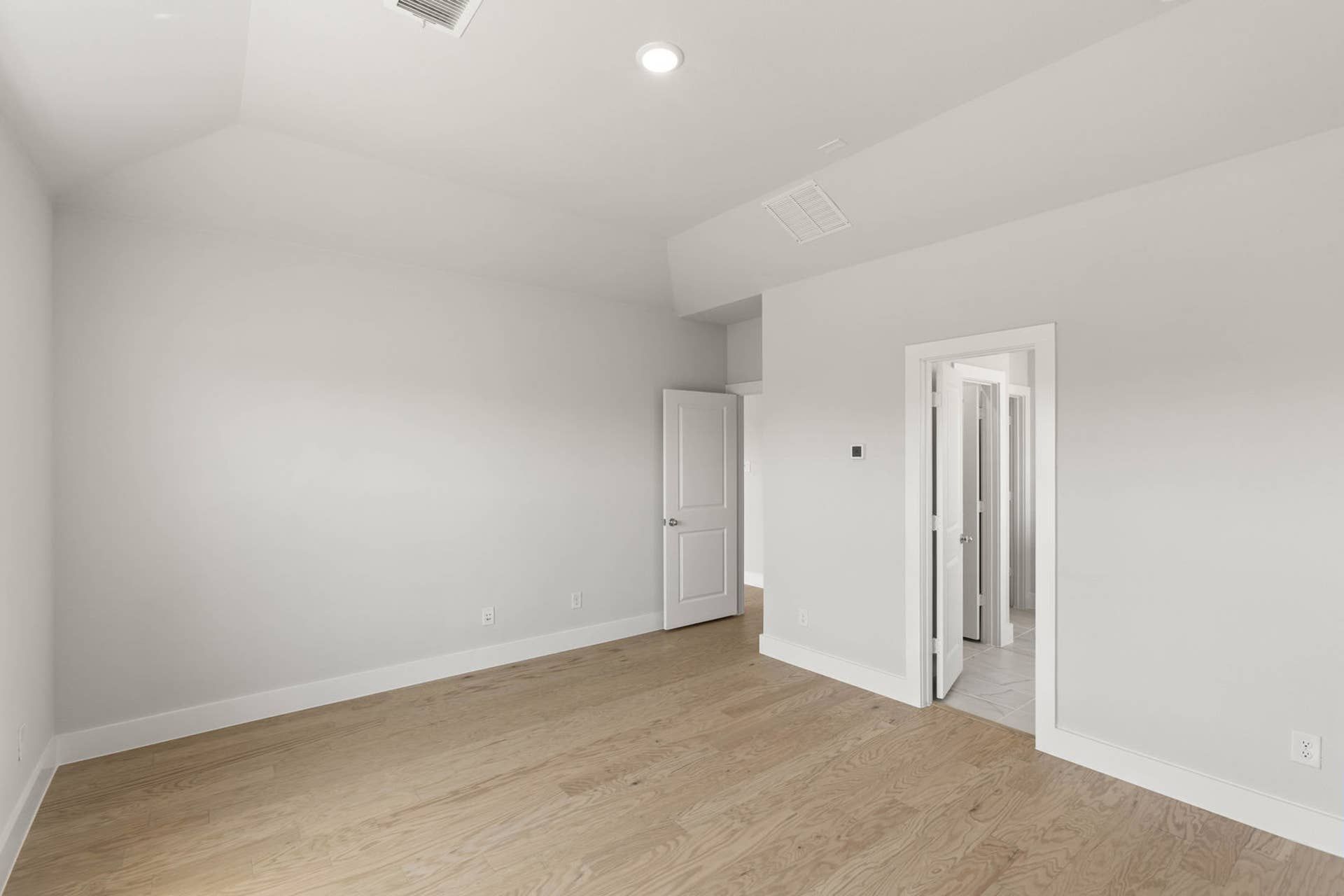 Spacious primary suite with hardwood floors and neutral walls.