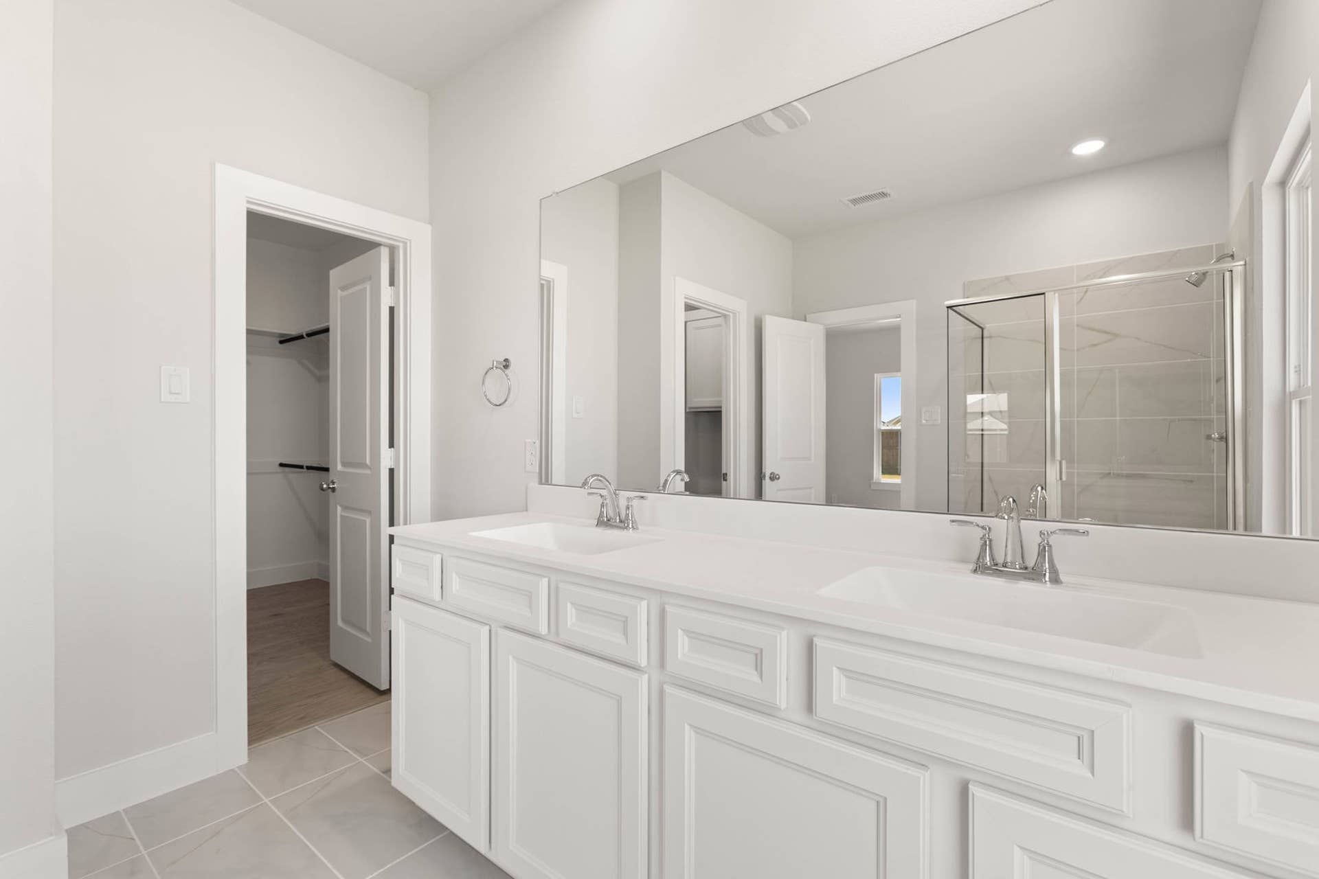 Spacious primary suite bathroom with dual sinks and glass-enclosed shower.