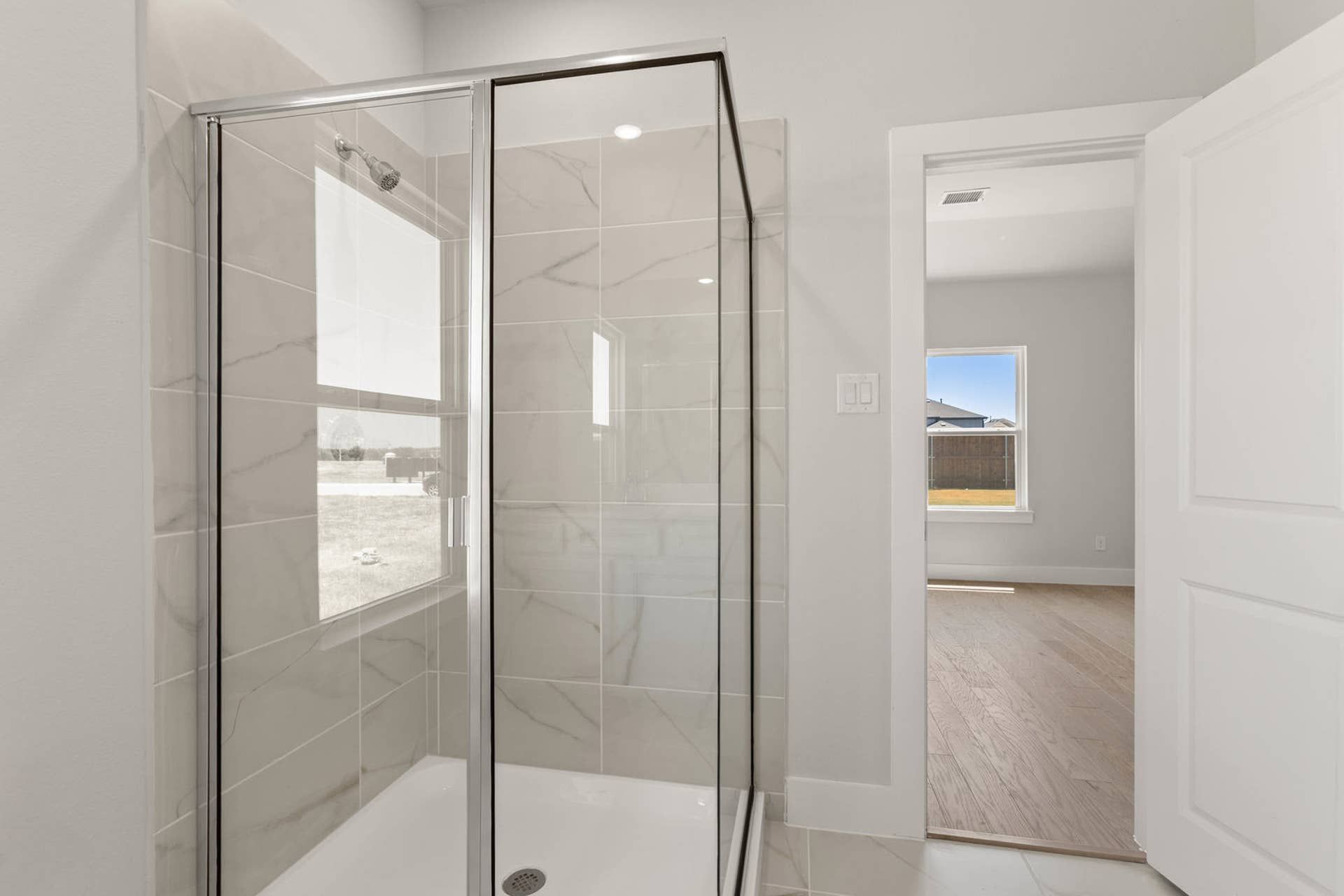 Modern bathroom with glass-enclosed shower and tiled walls.