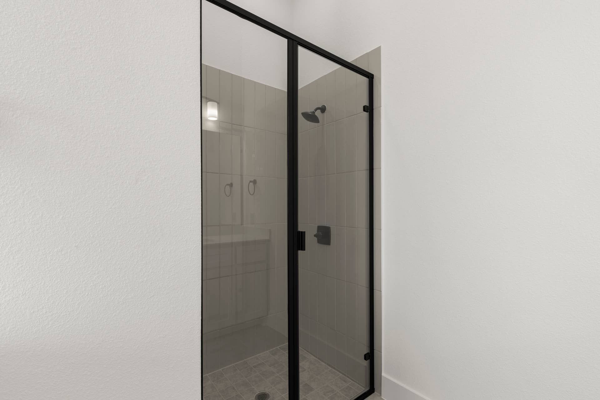 Modern bathroom with glass shower enclosure and sleek black fixtures.