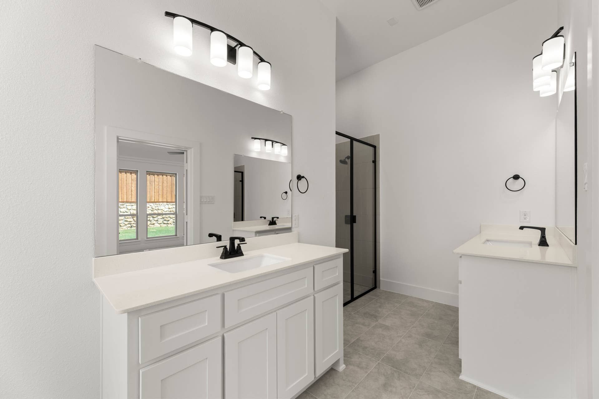 Modern bathroom with dual sinks, glass shower, and elegant lighting.