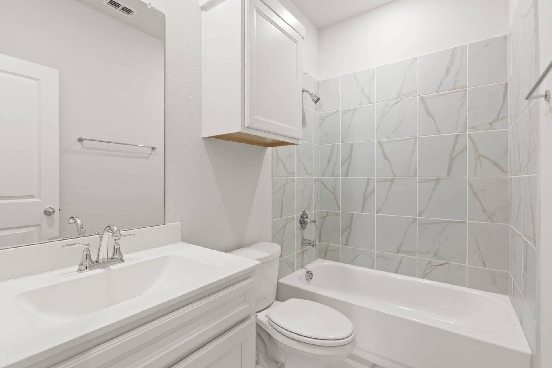 Modern bathroom with marble-tiled shower and white vanity.