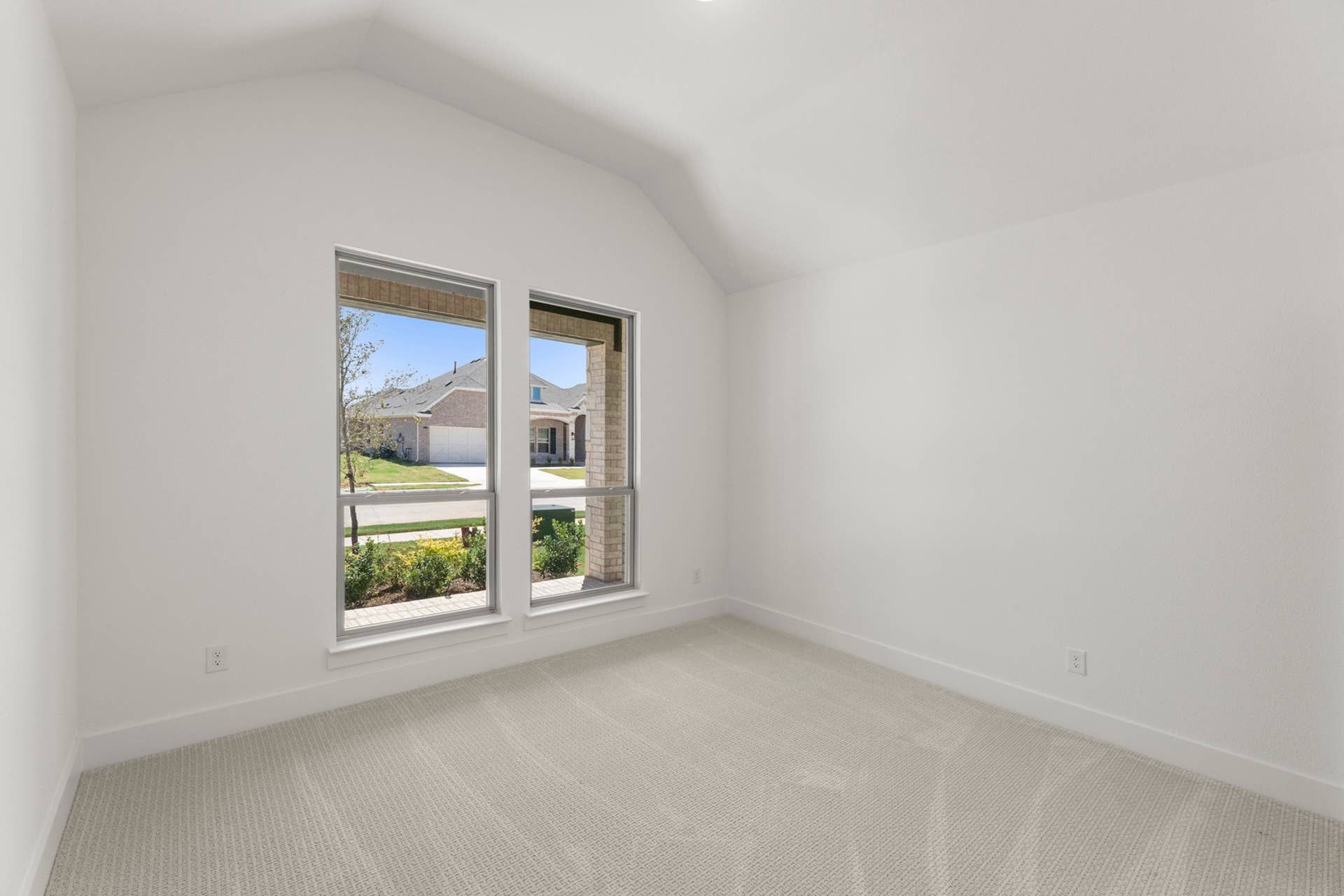 Bright bedroom with large windows and neutral carpeted flooring.