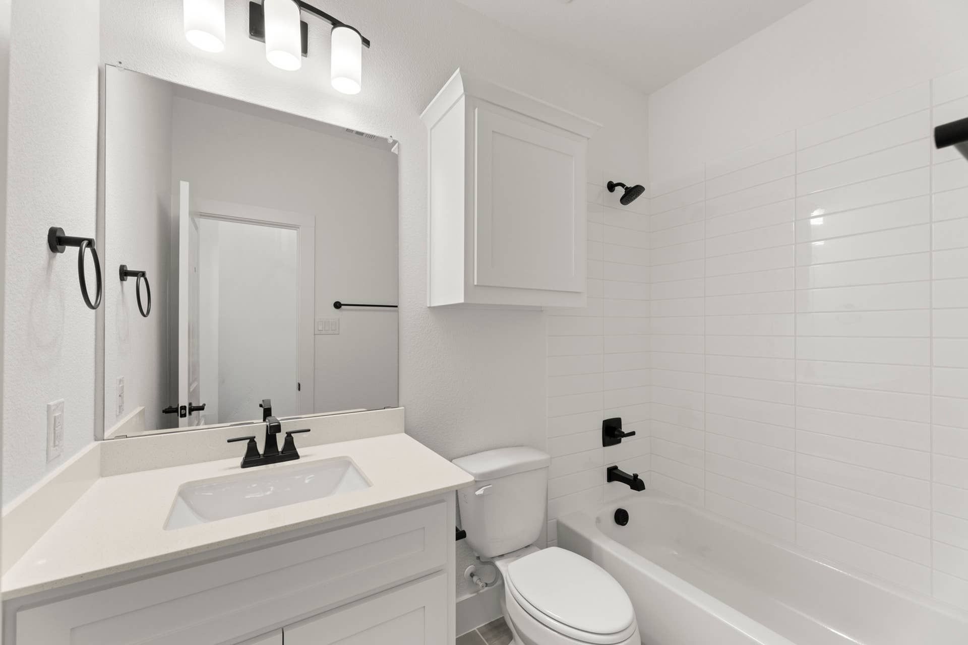 Modern white bathroom with black fixtures and a large mirror.