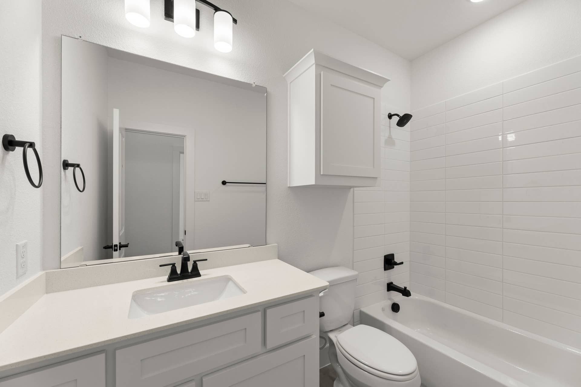 Modern bathroom with white cabinetry, sleek fixtures, and tiled bathtub.