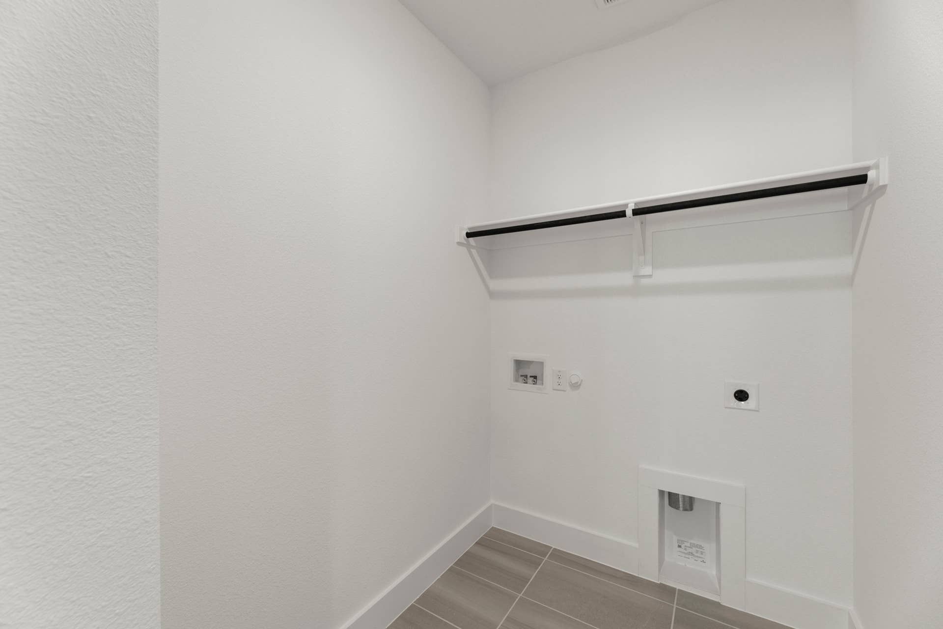 Utility room with white walls and tiled floor, featuring washer and dryer hookups.