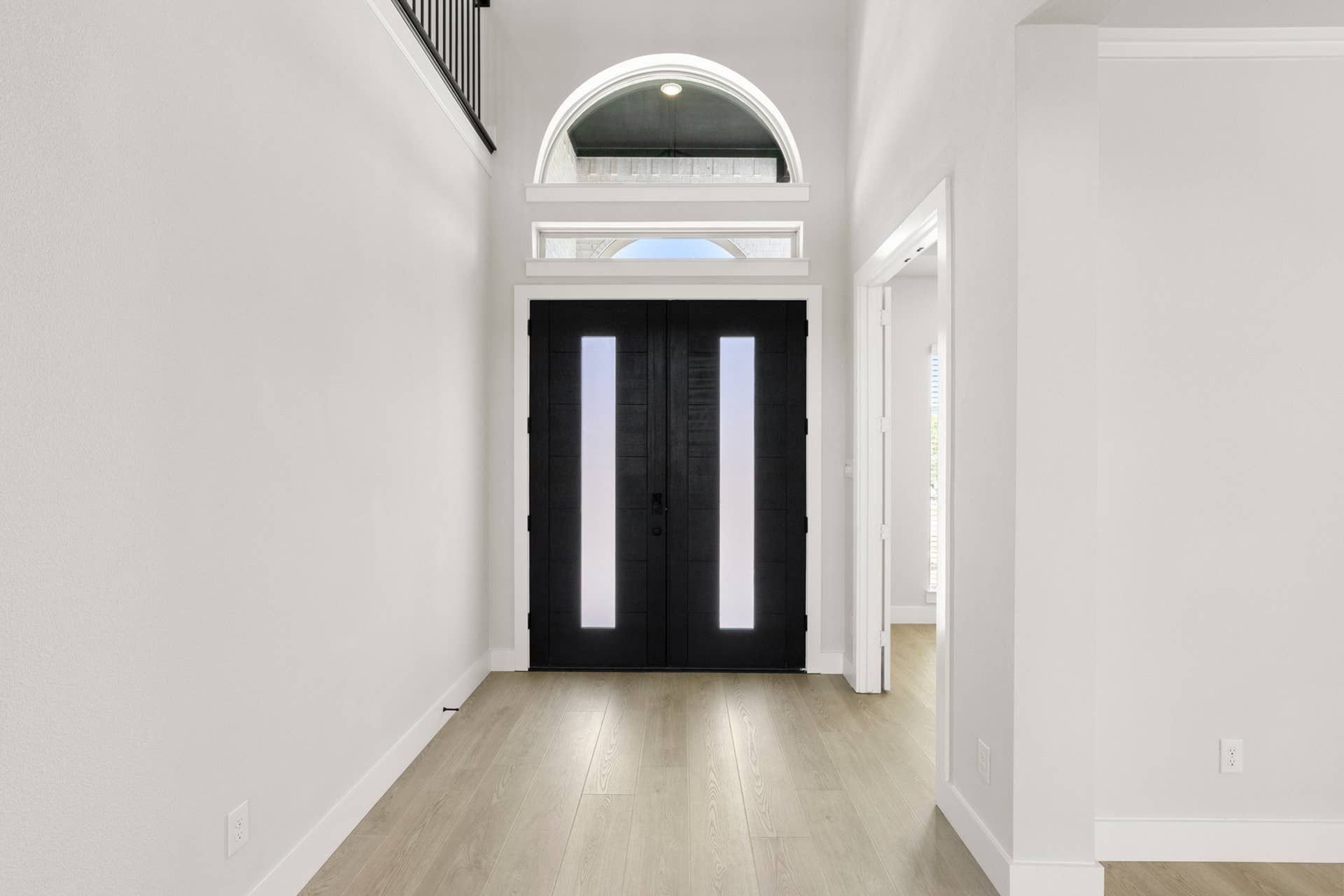 Spacious entryway with double doors and large arched window above.
