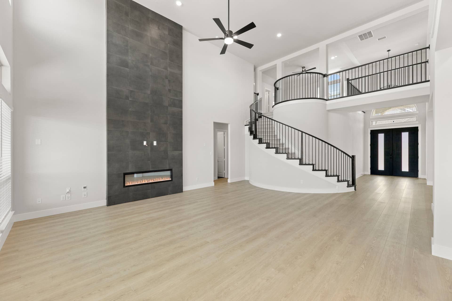 Spacious living area with modern fireplace and elegant curved staircase.