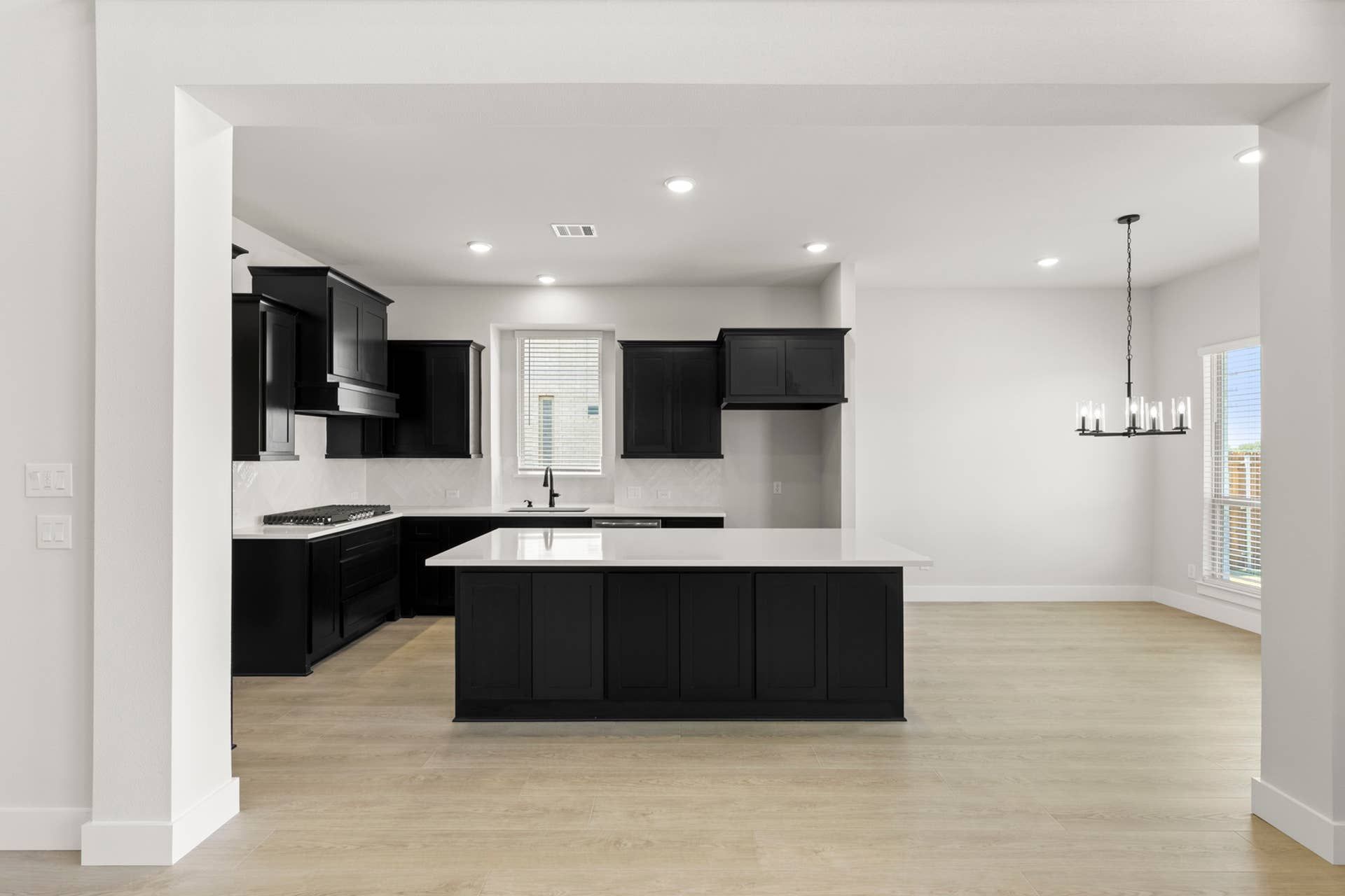 Modern kitchen with black cabinetry, island, and elegant chandelier lighting.